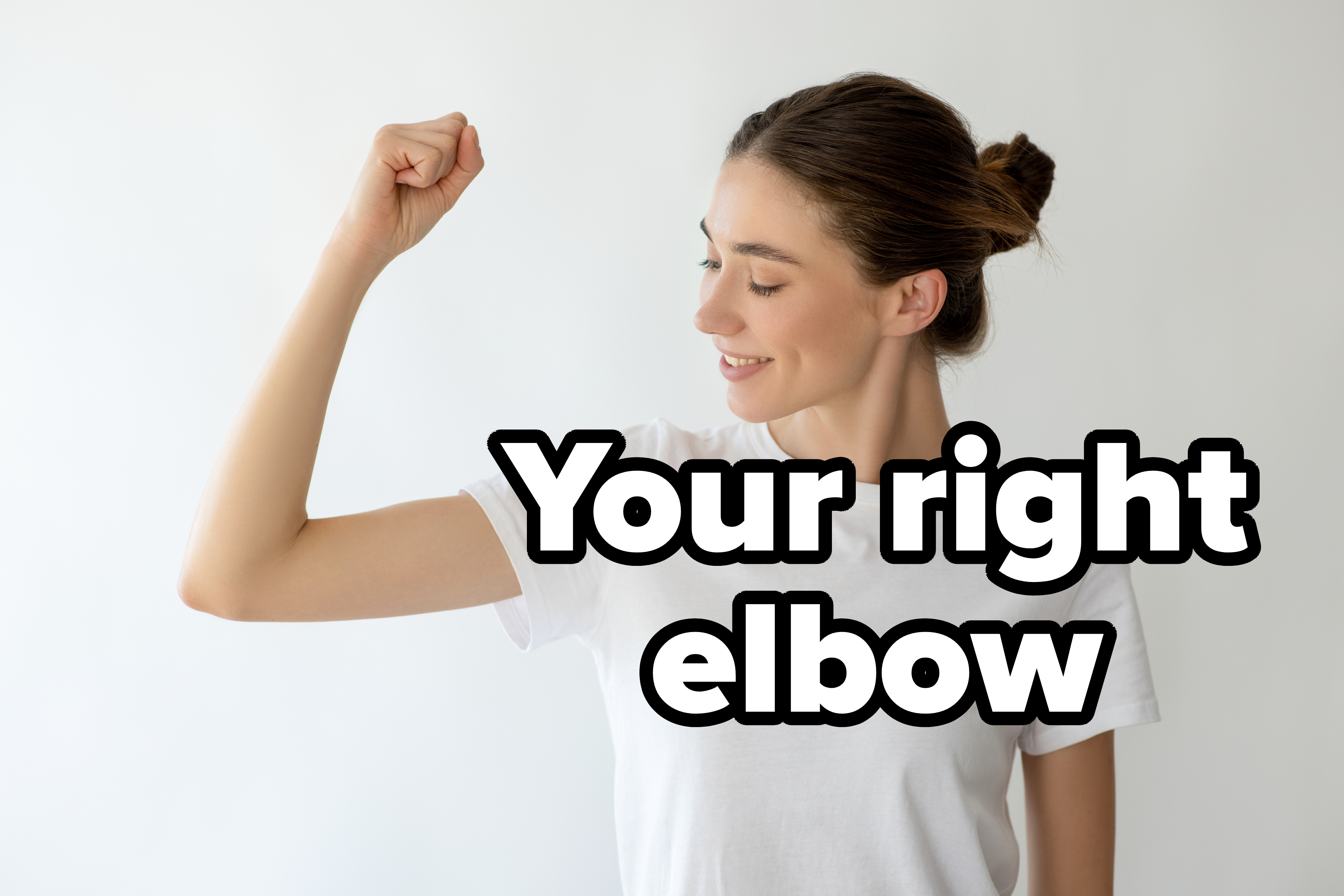A woman in a white t-shirt smiles and flexes her arm to show strength