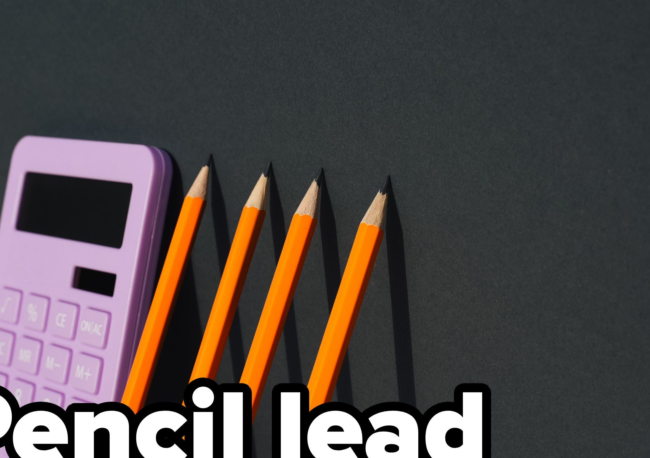 A calculator and four pencils arranged in a straight line on a flat surface