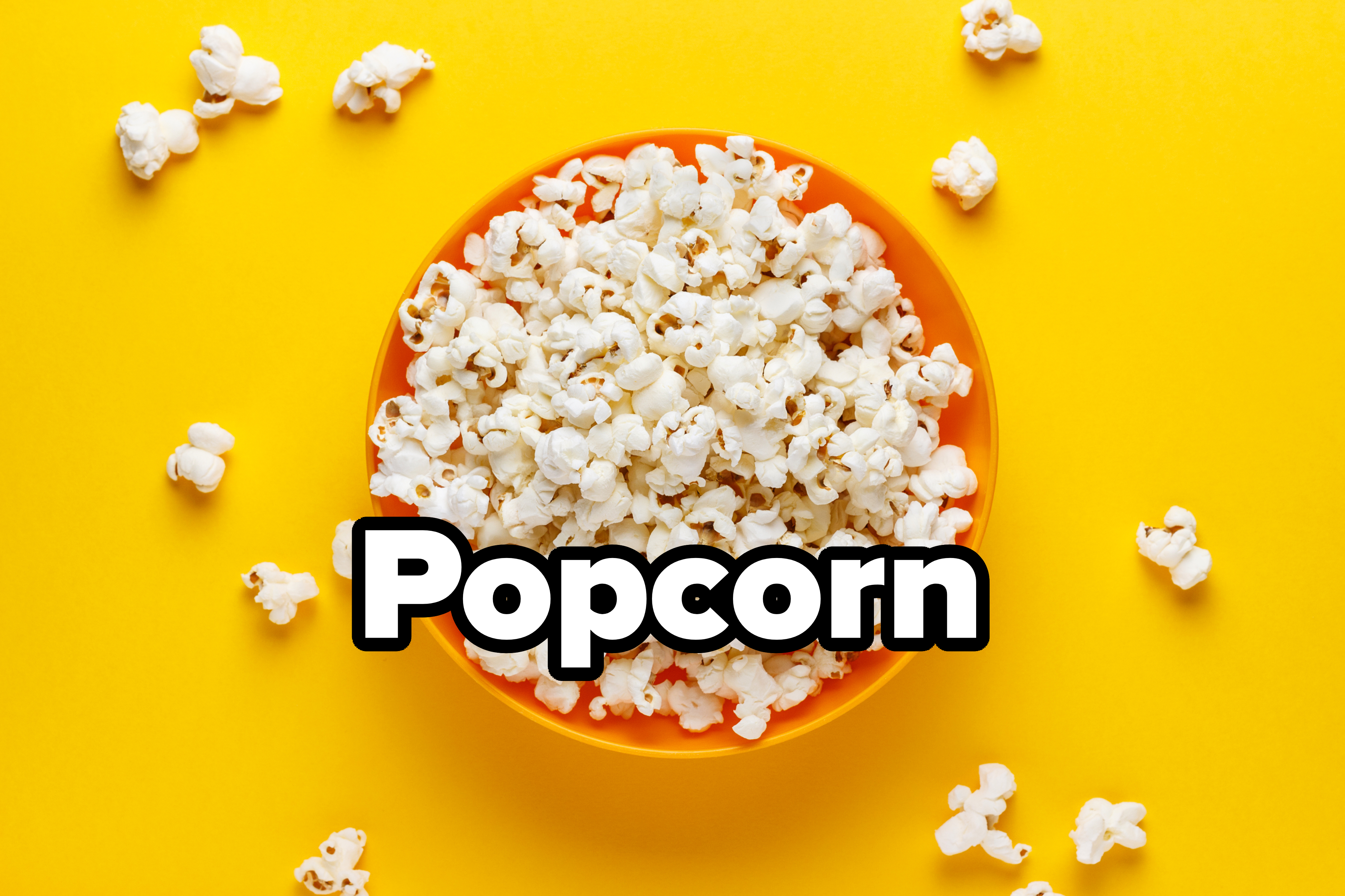 A bowl of popcorn surrounded by scattered popcorn pieces on a solid background