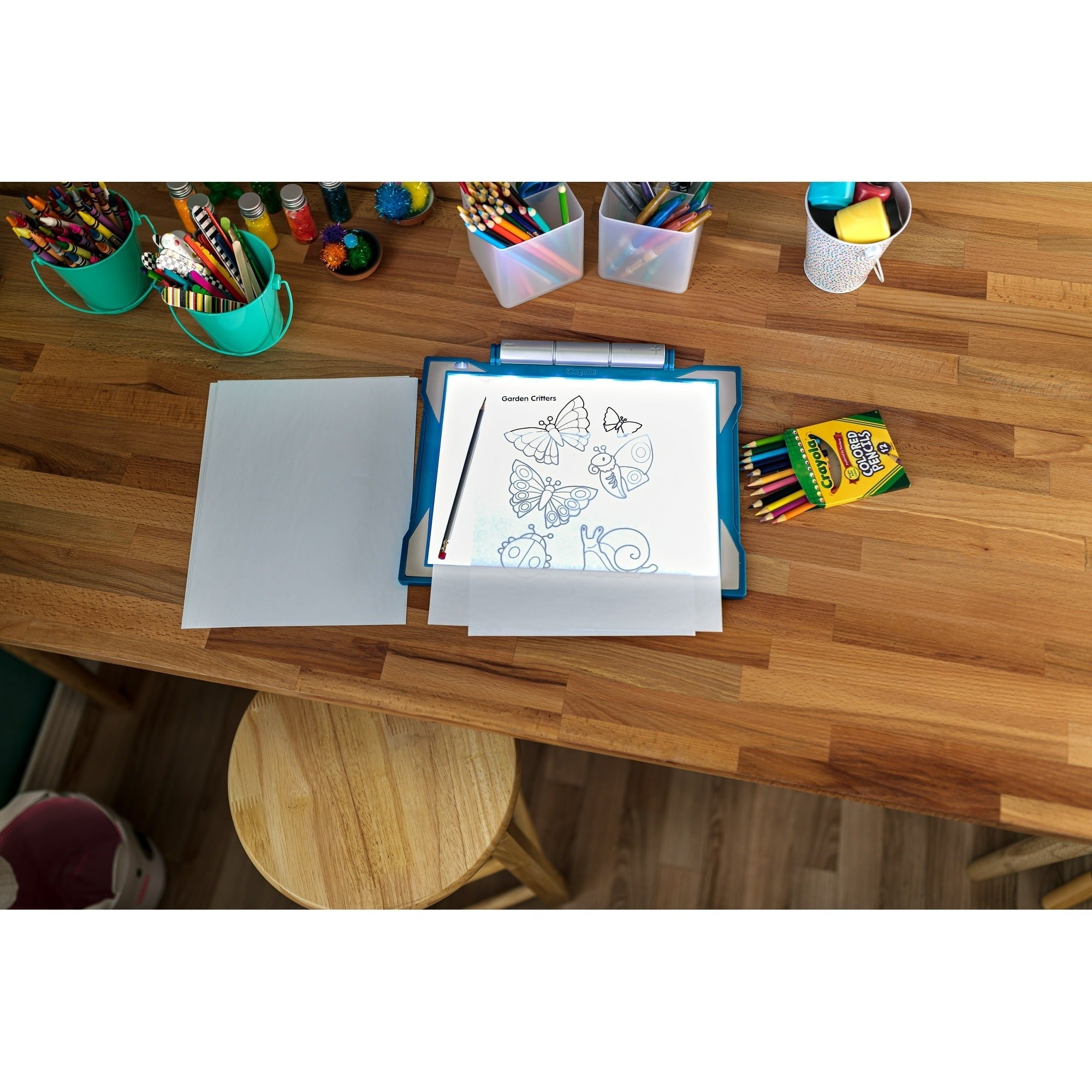Organized table  with coloring pages of butterflies, a folder, crayons, and assorted  colored pens successful  containers
