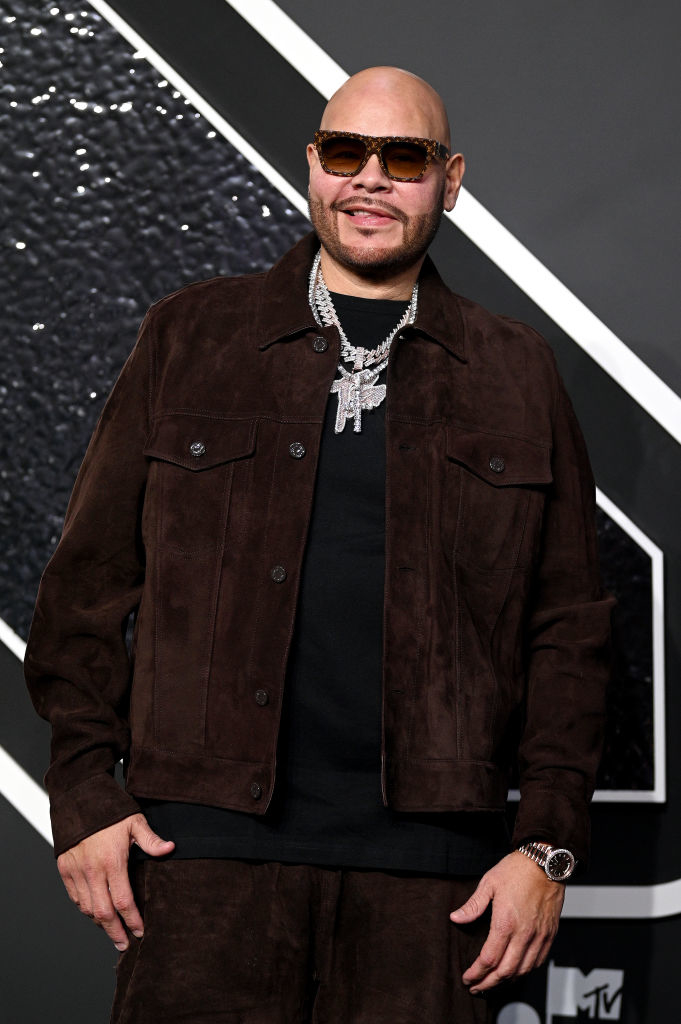 Fat Joe wearing a suede jacket, shirt, and sunglasses on the red carpet. He is also adorned with multiple necklaces