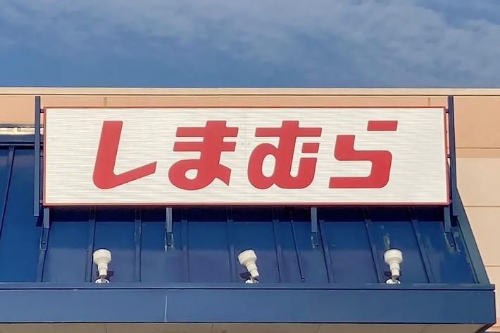 Sign on a building with Japanese text &ldquo;しまむら&rdquo; in red characters
