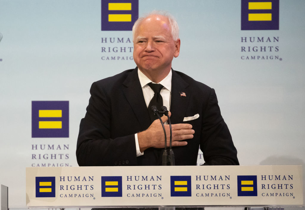Governor Tim Walz speaks behind a podium at a Human Rights Campaign event, wearing a suit and tie