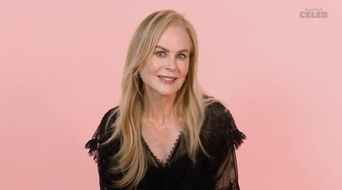 Nicole Kidman is posing and smiling, wearing a lace dress with sheer sleeves