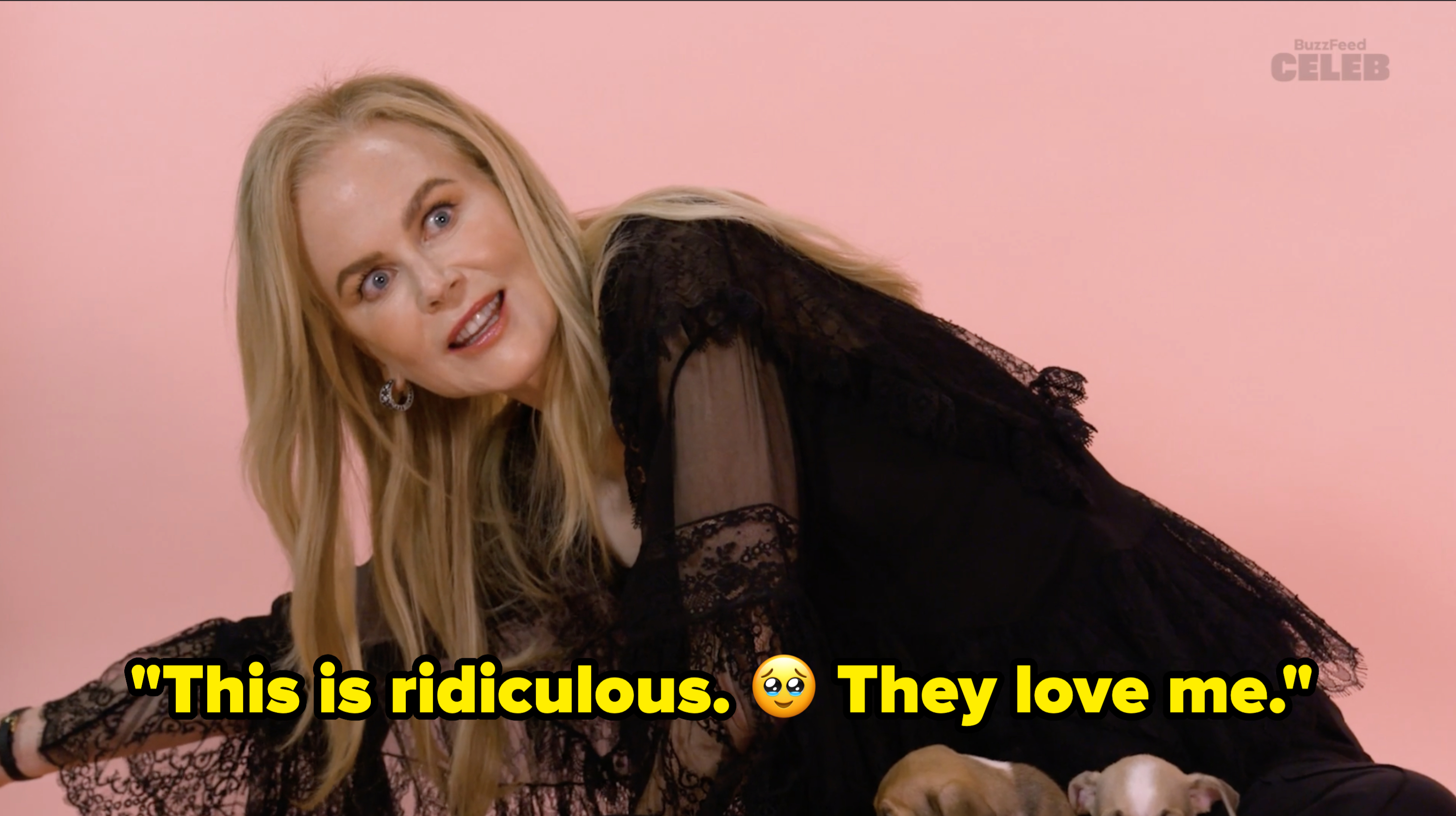 Nicole Kidman in a playful pose wearing a lace dress while playing with puppies