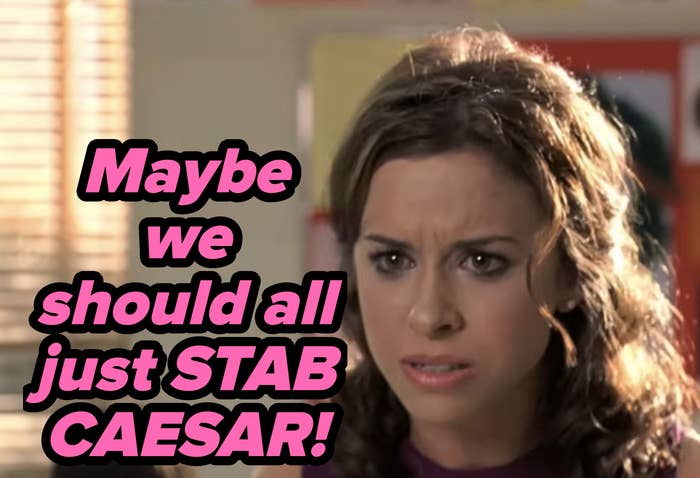 Woman with curly hair looks intently and appears concerned in a room with posters on the wall