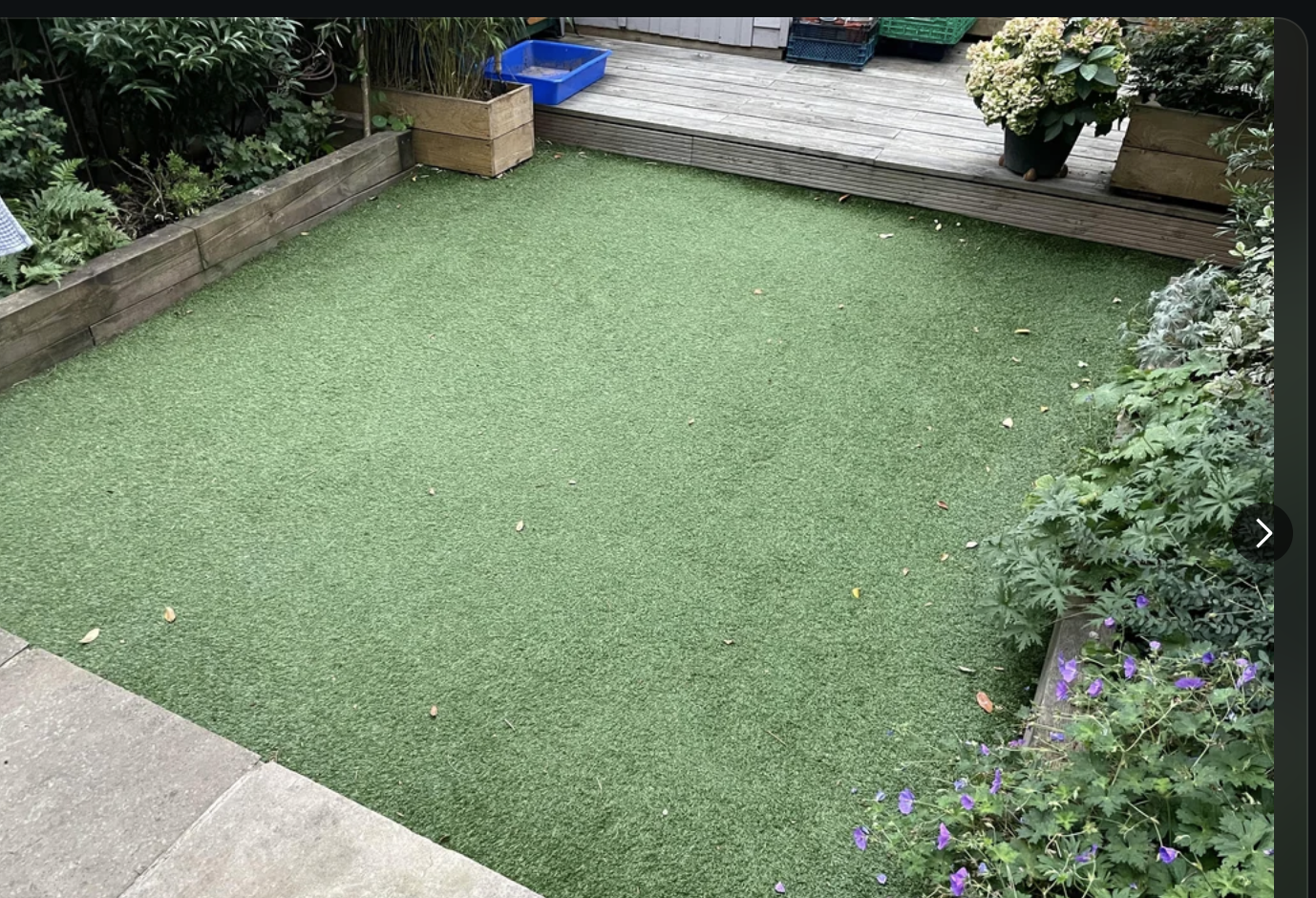 A Reddit post in r/GardeningUK showing a backyard with artificial grass. The user is asking for advice on replacing fake grass with real grass
