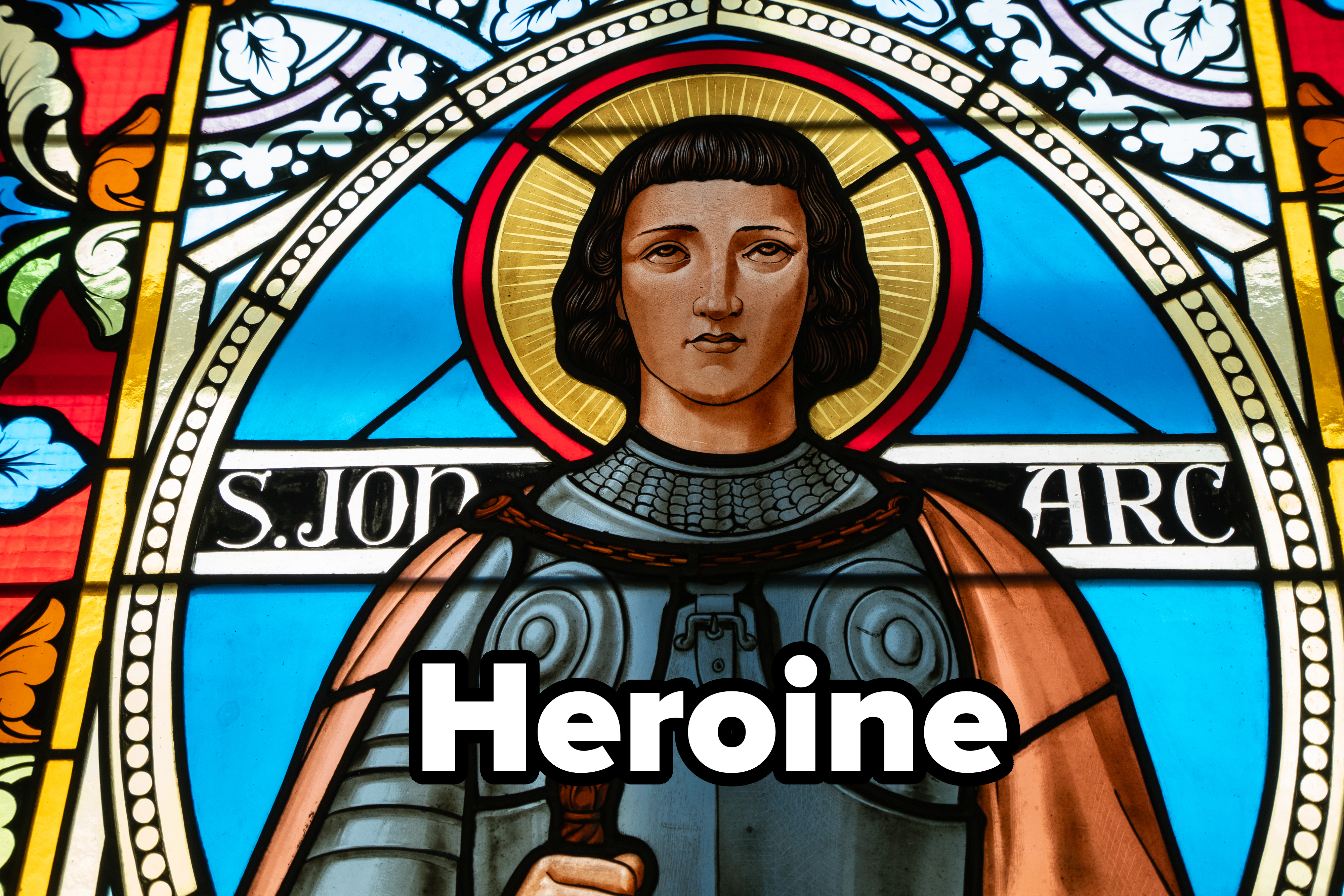 Stained glass depiction of Joan of Arc, showcasing intricate armor and a halo, surrounded by floral patterns and the inscription "S. Jo ARC."