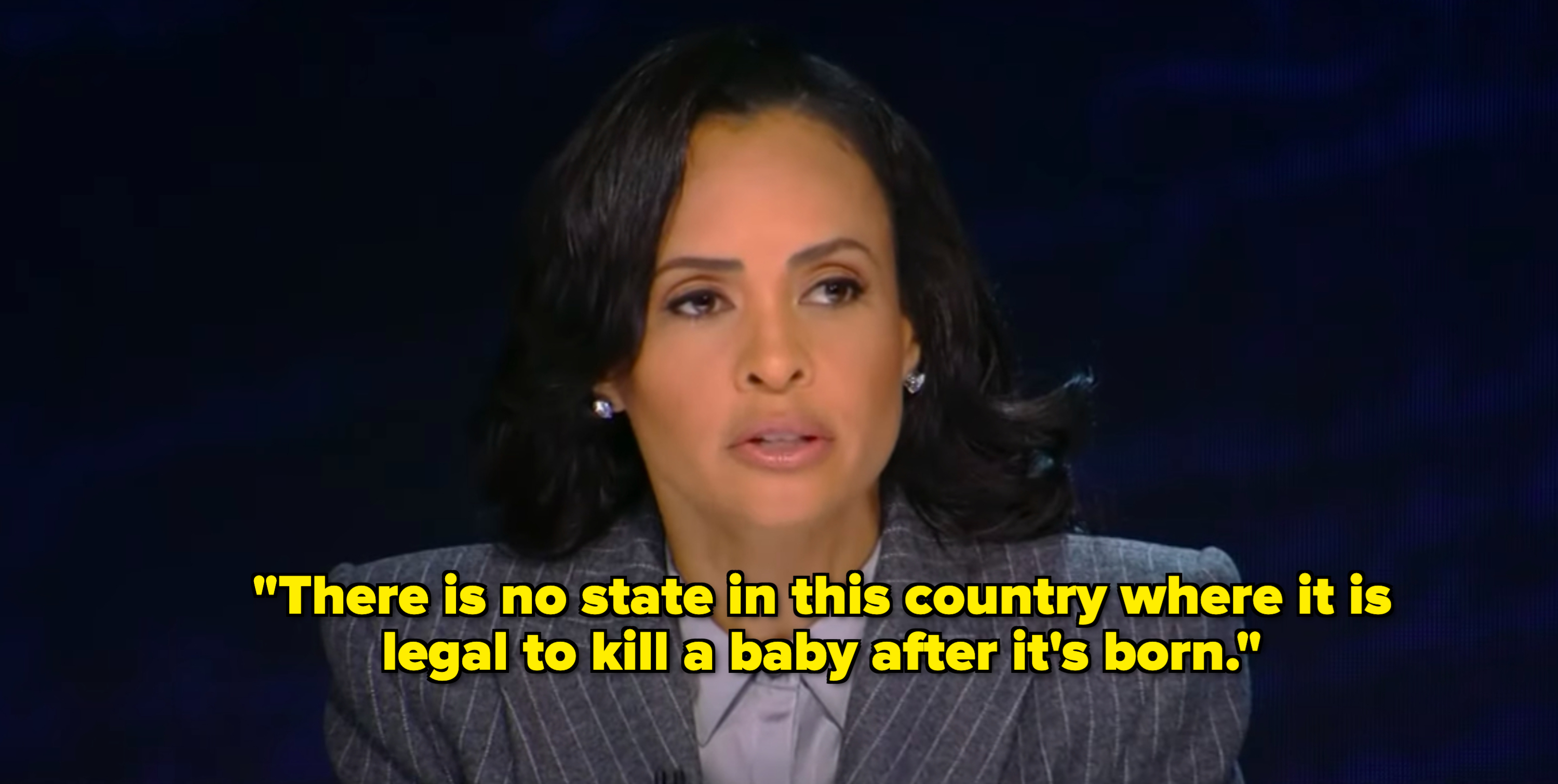 Veronica Webb is sitting and speaking, dressed in a pinstriped suit jacket with a collared shirt beneath