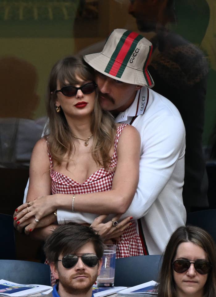 Travis with his arms around Taylor from behind as they watch the US Open