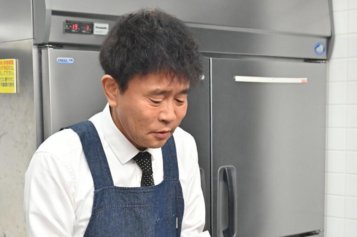 厨房で魚の串焼きを準備している料理人。