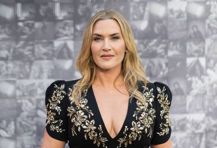 Kate Winslet on the red carpet wearing an elegant dark gown with intricate embellishments