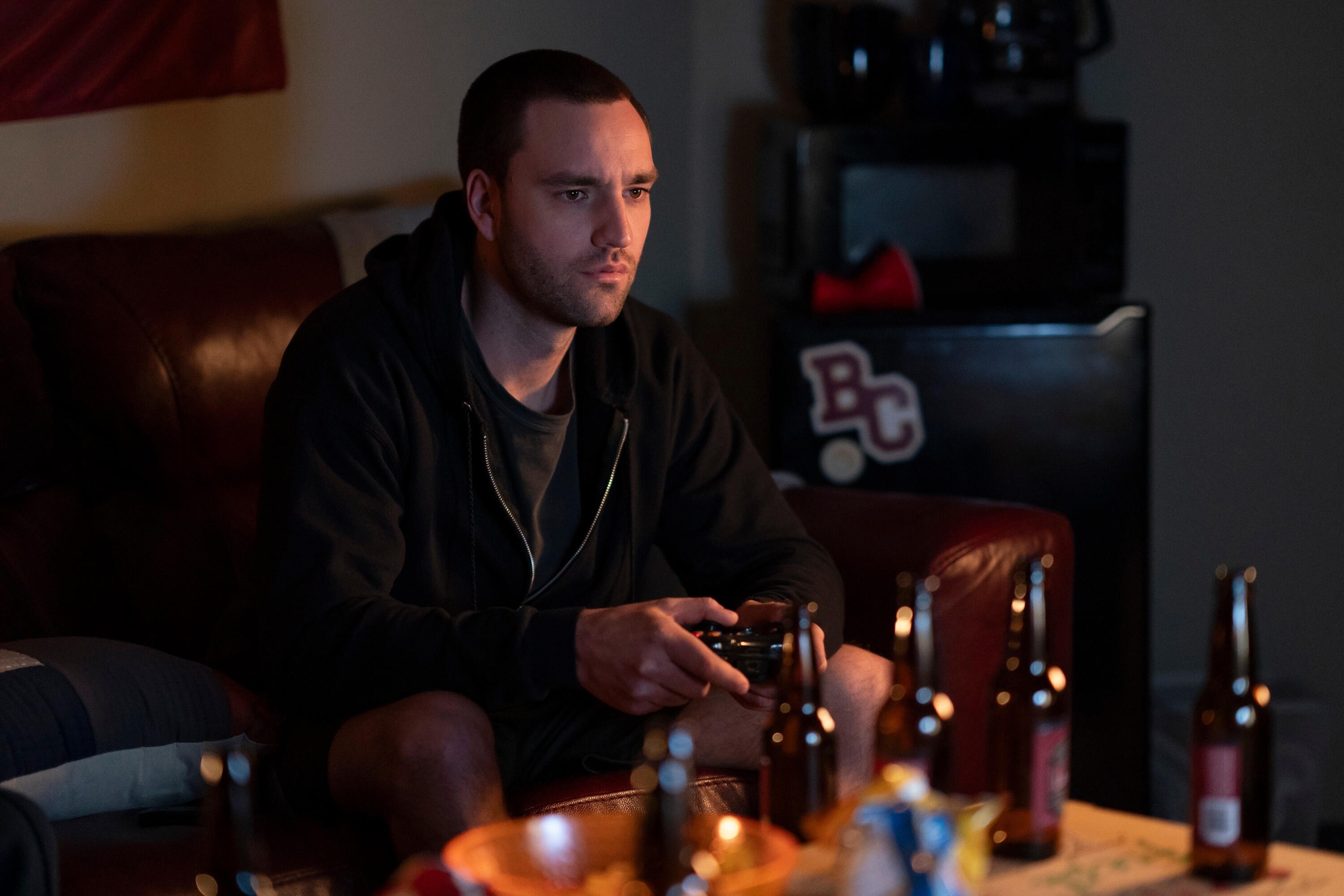 Jackson White playing video games with beer bottles sitting on a table in front of him in "Tell Me Lies"