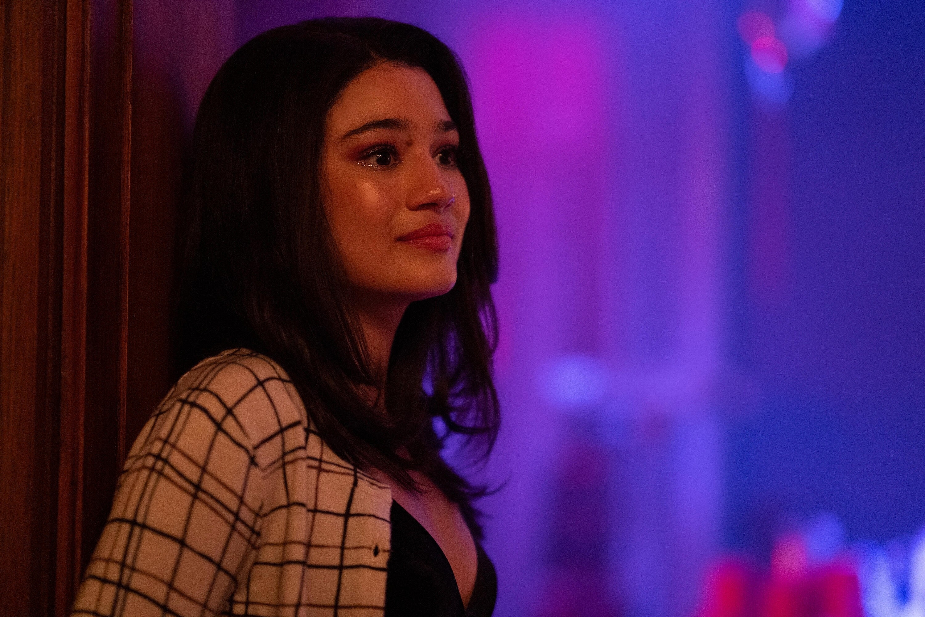 Alicia Crowder in a plaid sweater and black top in "Tell Me Lies"