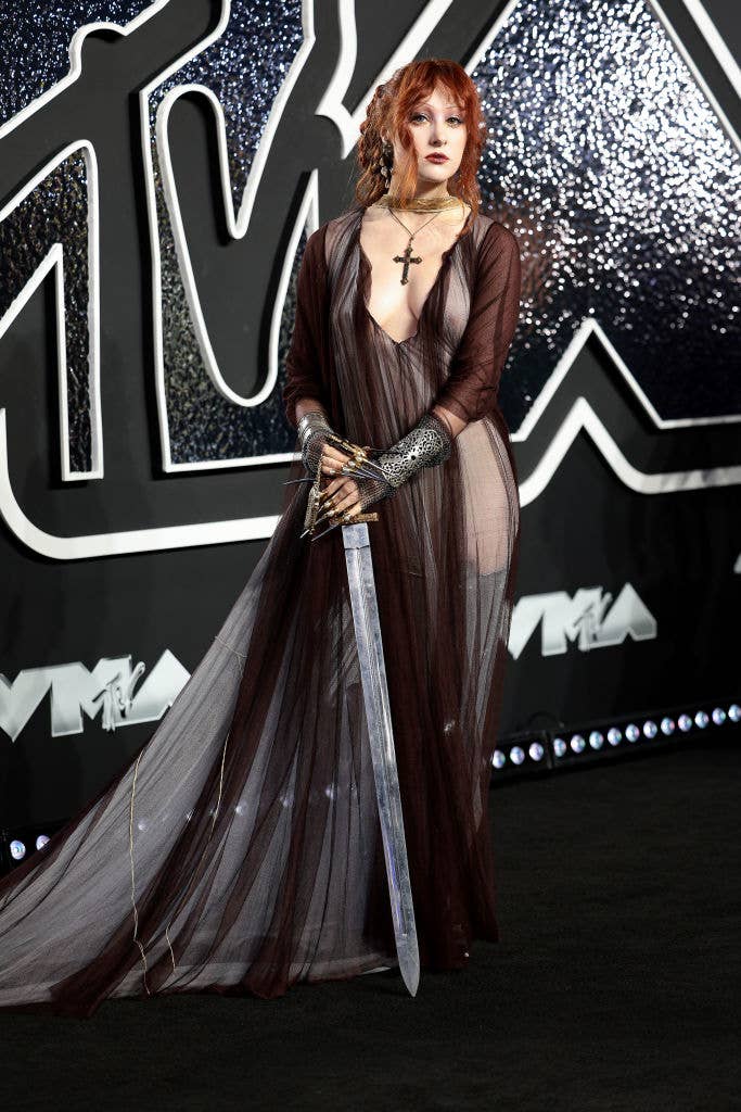 Chappell Roan on the MTV Video Music Awards red carpet, wearing a sheer gown with metallic gloves, holding a sword
