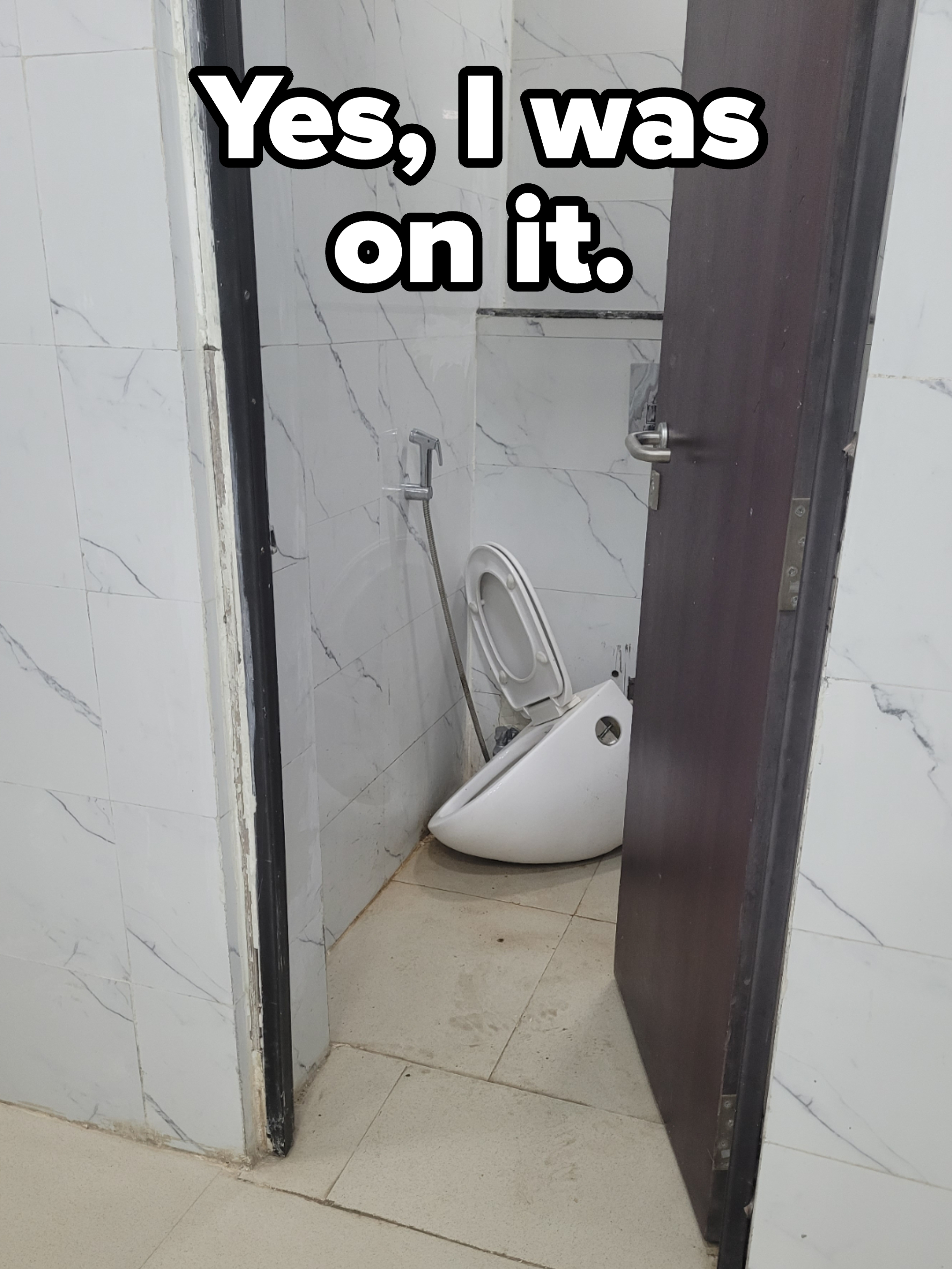 A small restroom with a broken toilet bowl leaning against the wall next to the toilet seat, apparently detached from its base