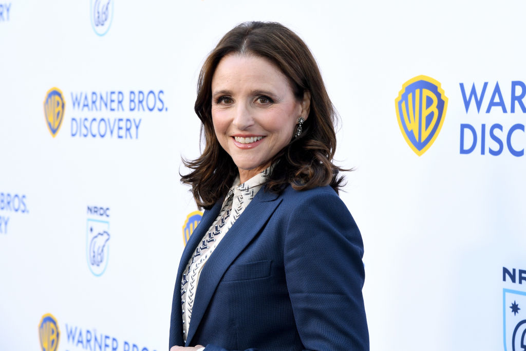 Julia Louis-Dreyfus at a Warner Bros. Discovery event, wearing a tailored suit and smiling at the camera