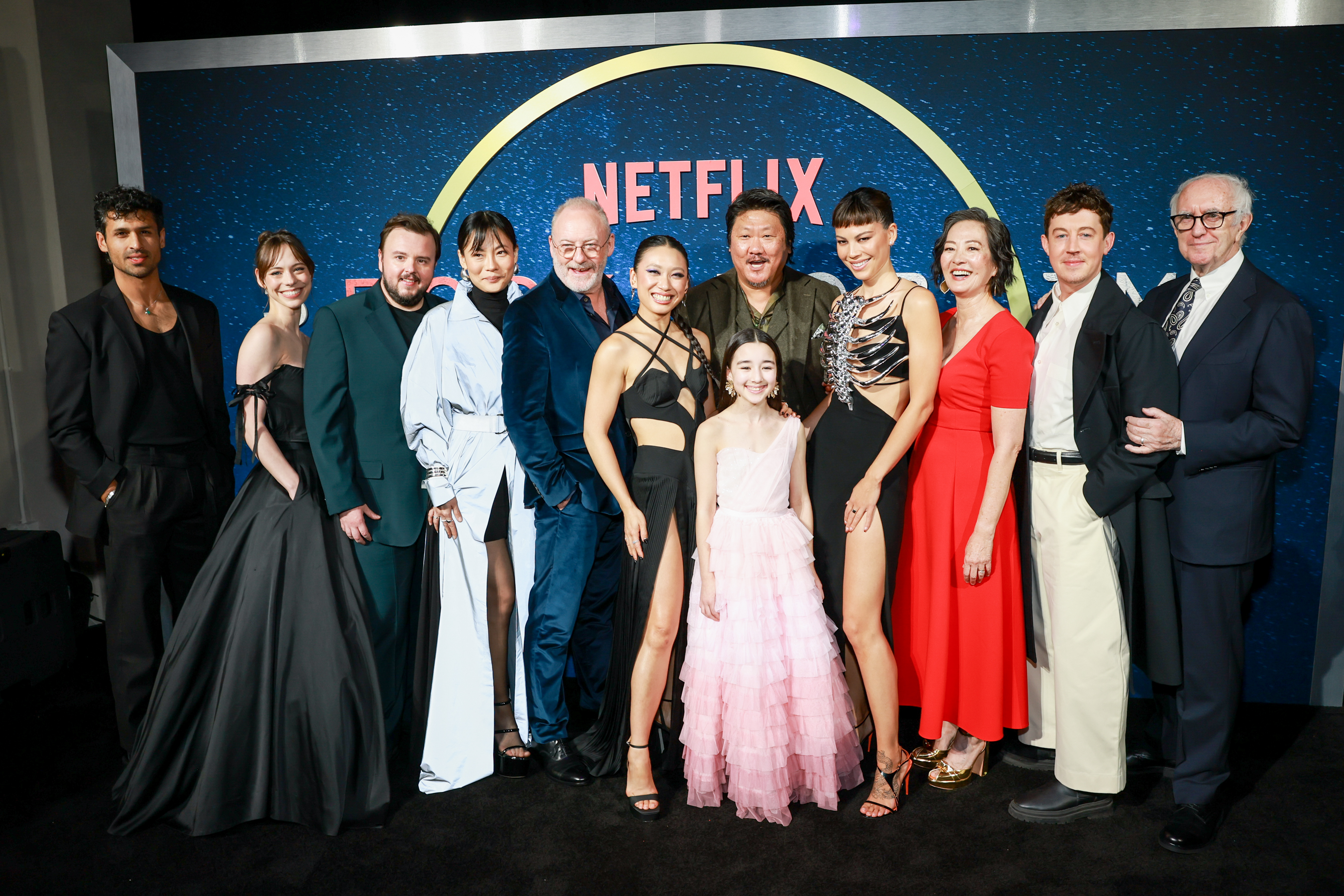 A group photo of 12 people dressed in elegant attire, at a Netflix event