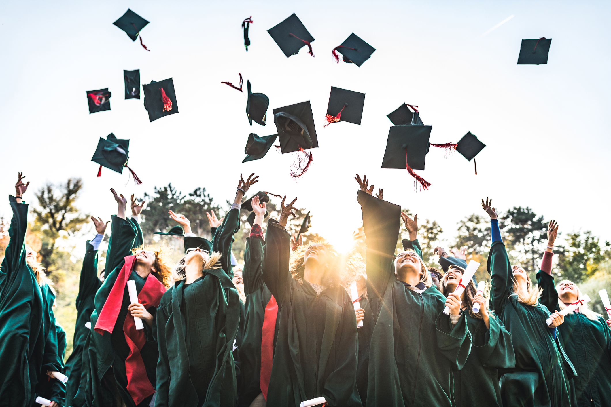 Graduates in caps and gowns celebrate by tossing their caps into the air