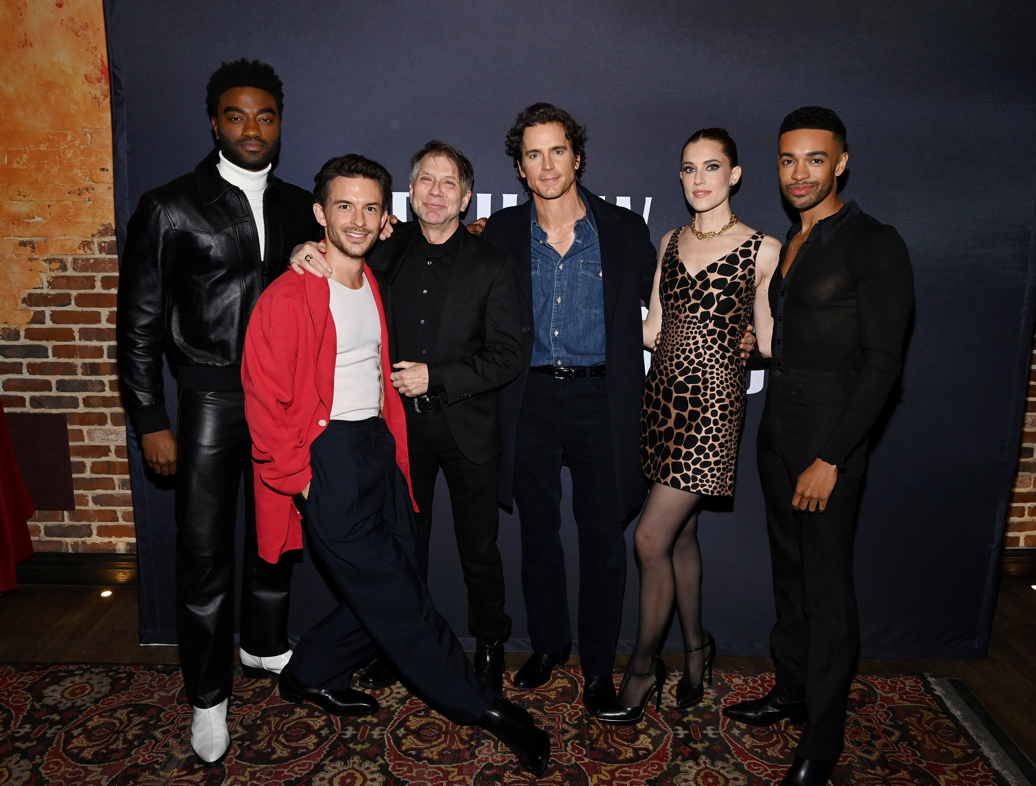 Six people at an event posing together in stylish attire