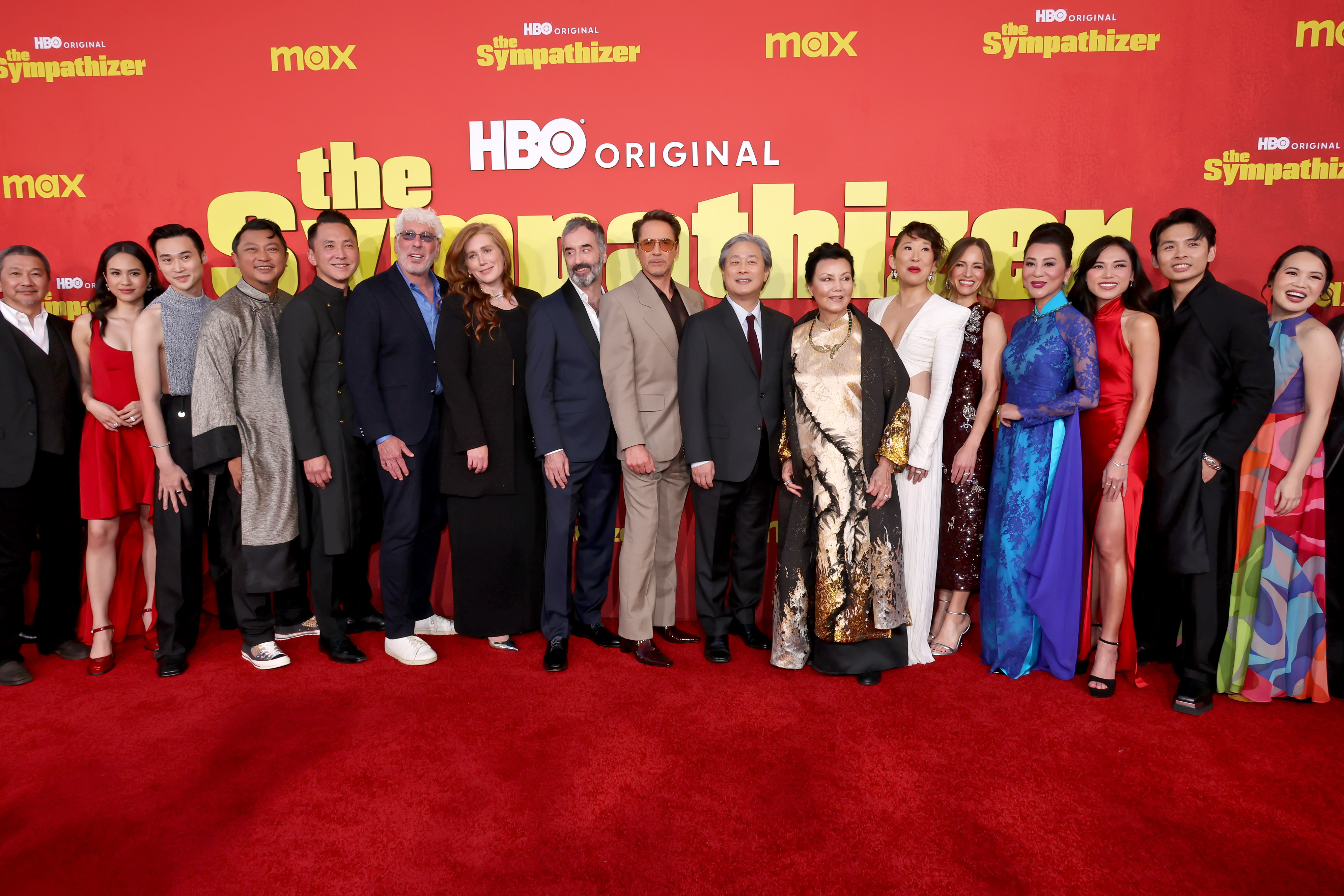The cast of 'The Sympathizer' at the HBO Original red carpet event, dressed in formal and traditional attire, posing together for a group photo