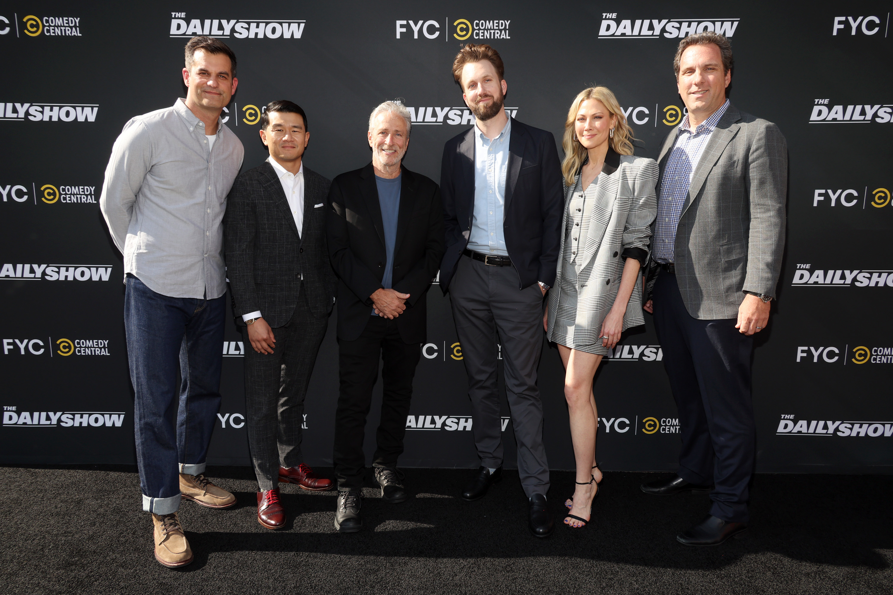 Steve Carell, Ronny Chieng, and four others in business-casual attire pose on the red carpet at a Comedy Central event for The Daily Show