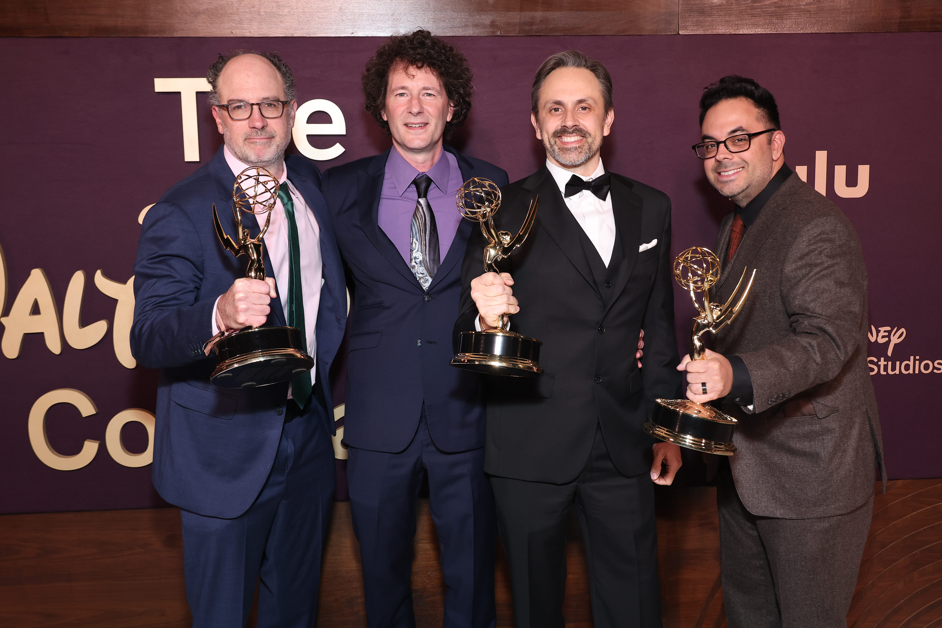 Four men pose with their Emmy awards