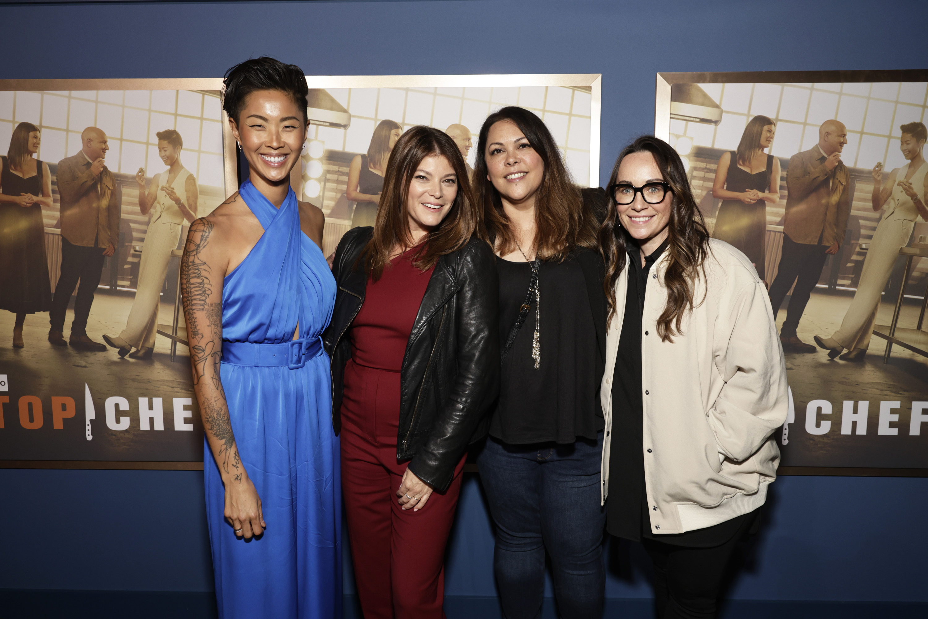 Four people pose standing in front of "Top Chef" poster