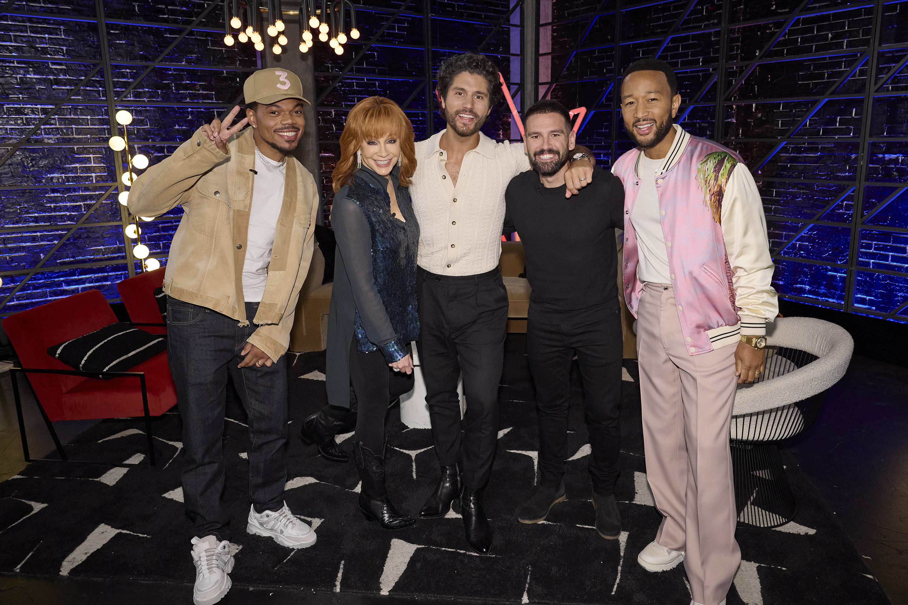 Chance the Rapper, Reba McEntire, Niall Horan, Ben Allen, John Legend are posing on set. Chance makes a peace sign with fingers, and others smile at the camera