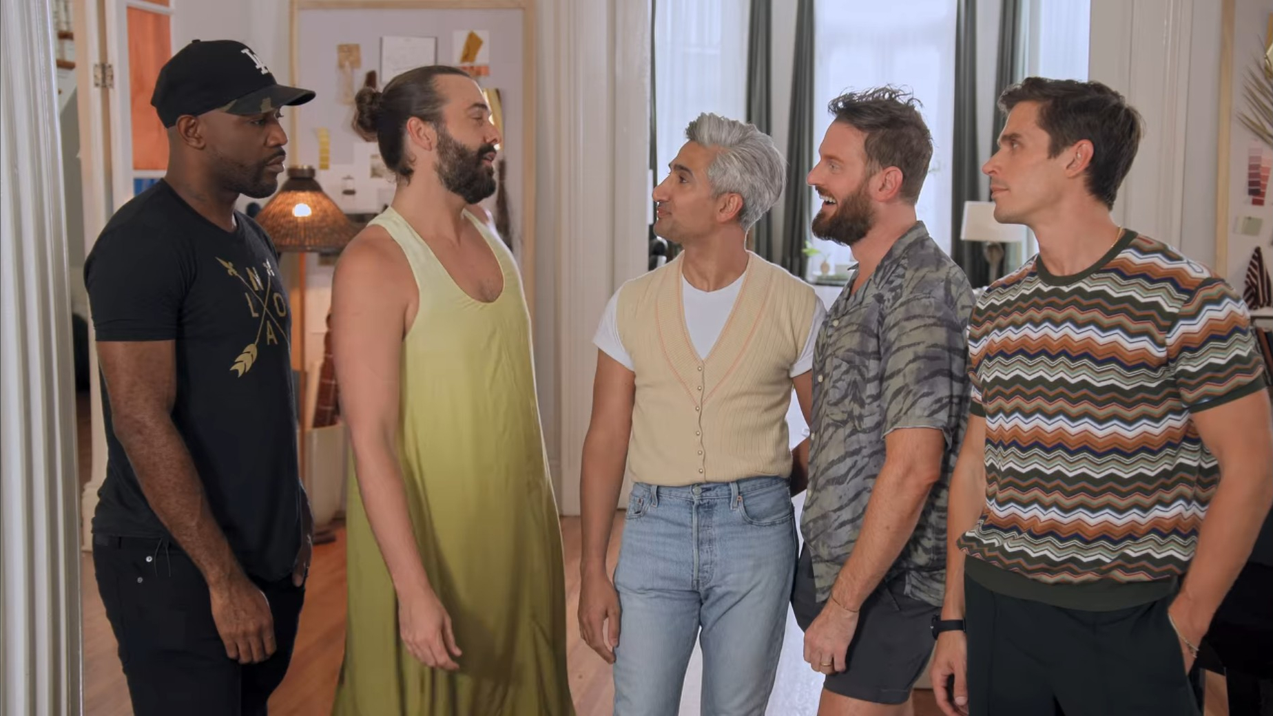 Five guys together indoors, looking at each other and chatting