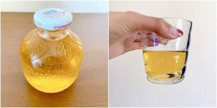 リンゴジュースの瓶が左側にあり、右側には手で持ったグラスに注がれたリンゴジュースがあります。