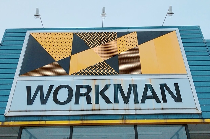 A storefront with a large sign displaying &ldquo;WORKMAN&rdquo; and geometric patterns above the entrance