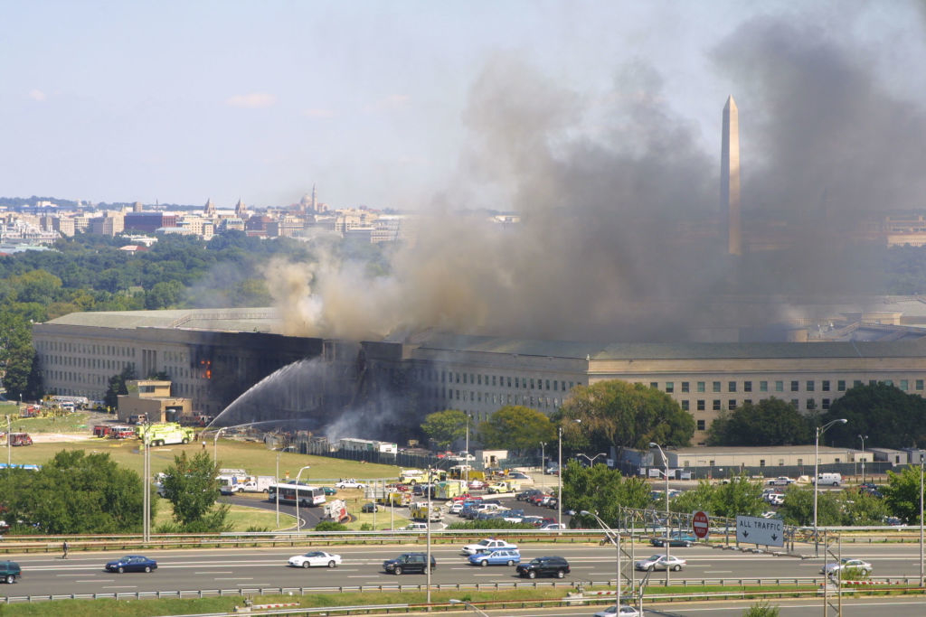 Smoke rises from the Pentagon as firefighters work to extinguish the flames after the 9/11 attack. The Washington Monument is visible in the background