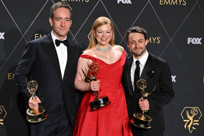 Matthew Macfadyen, Sarah Snook, and Kieran Culkin holding Emmy Awards at the Emmys event. They are dressed in formal attire