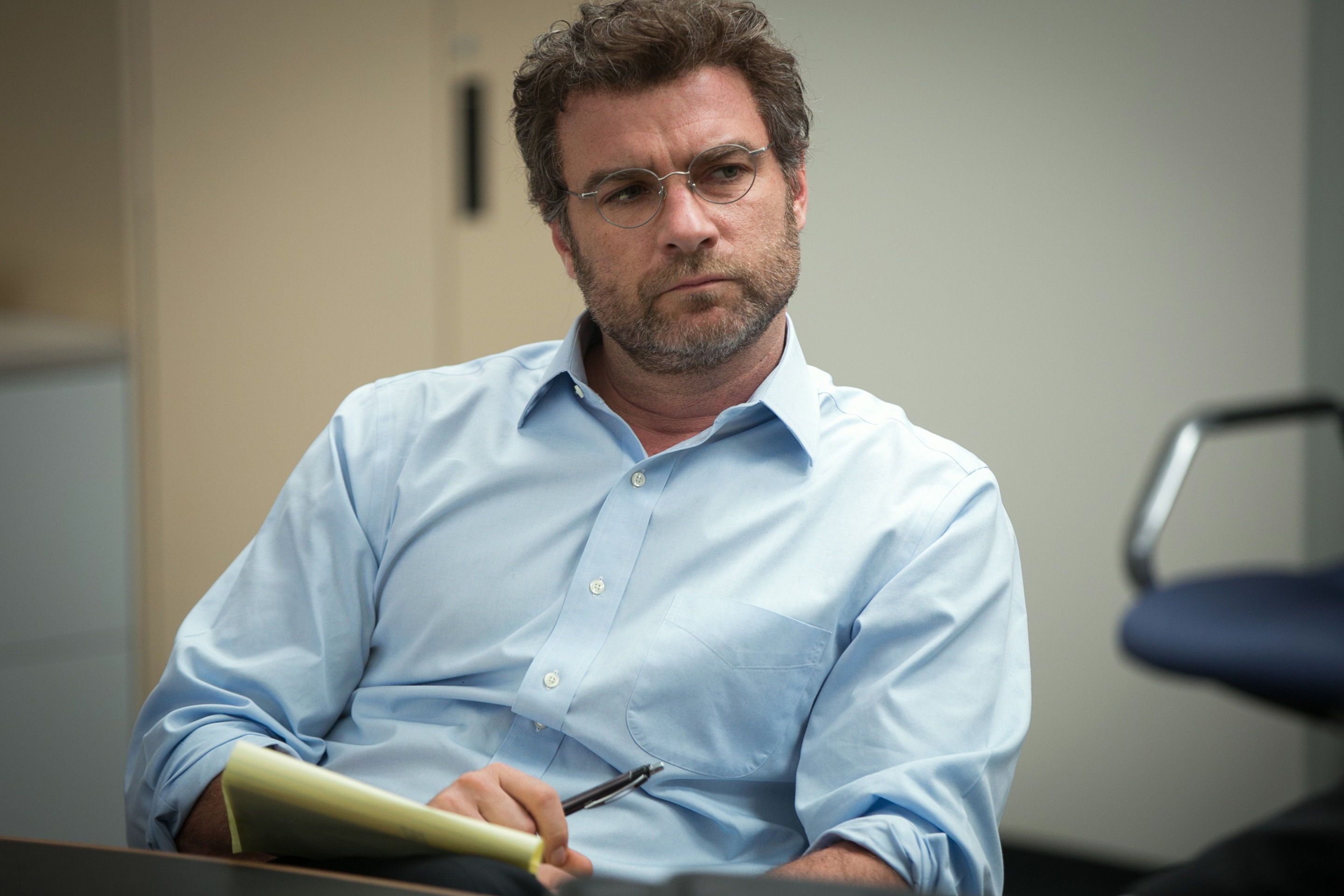 Liev Schreiber in a button-up shirt, holding a notepad in "Spotlight"