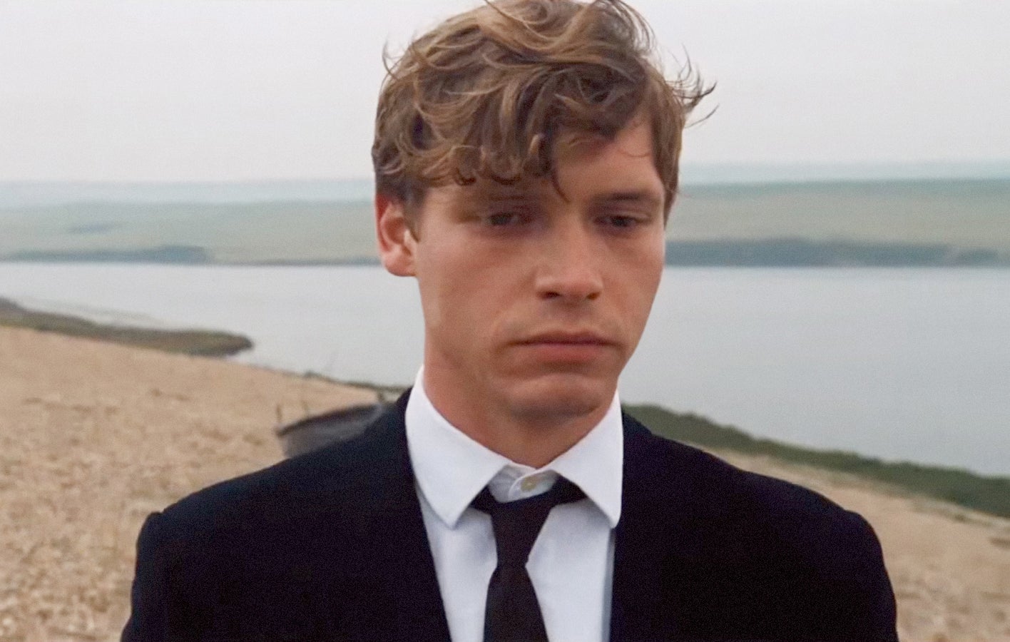 Billy Howle in a suit on the beach in "On Chesil Beach"