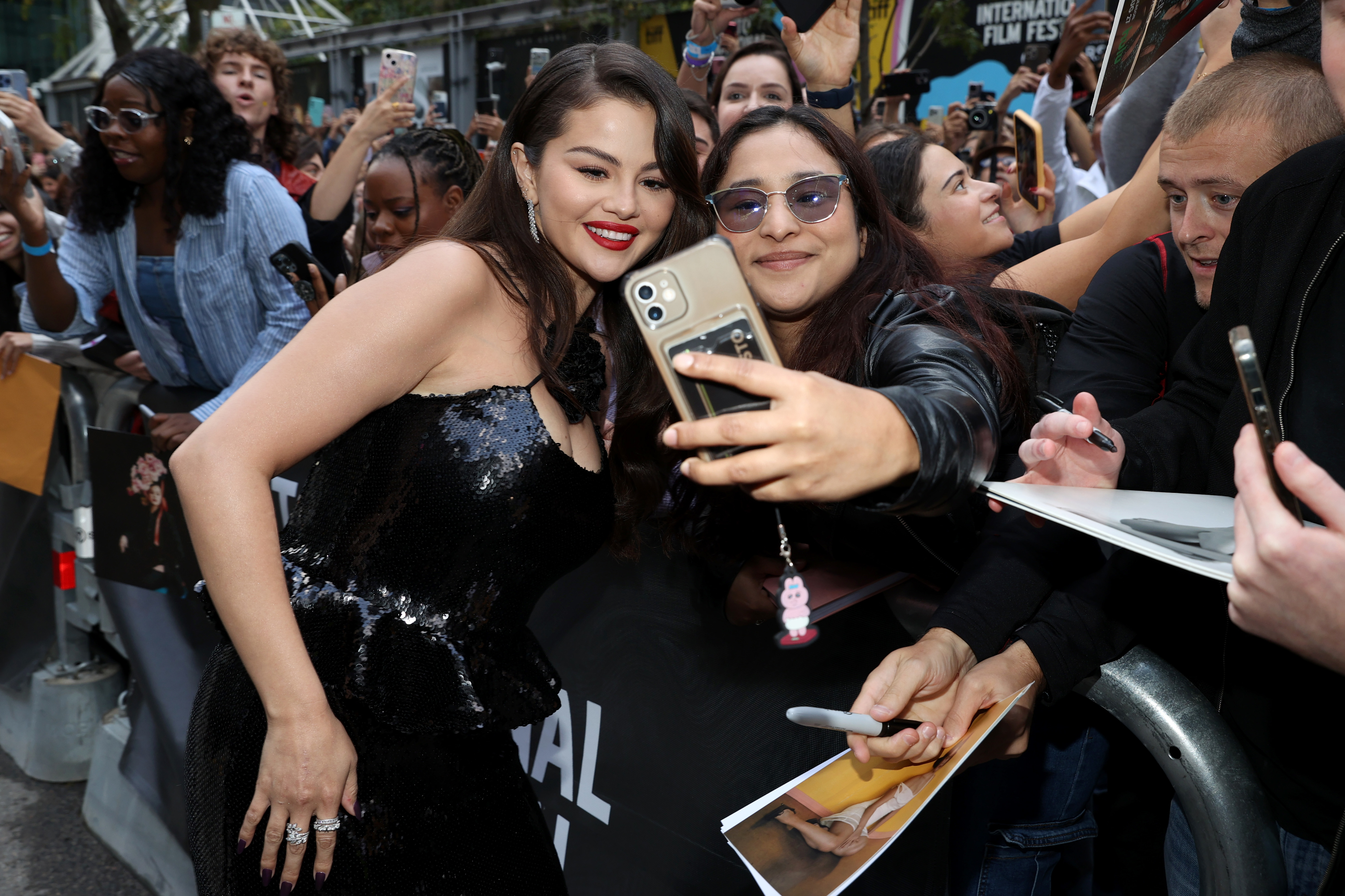 Selena Gomez poses with fans, taking selfies at an event