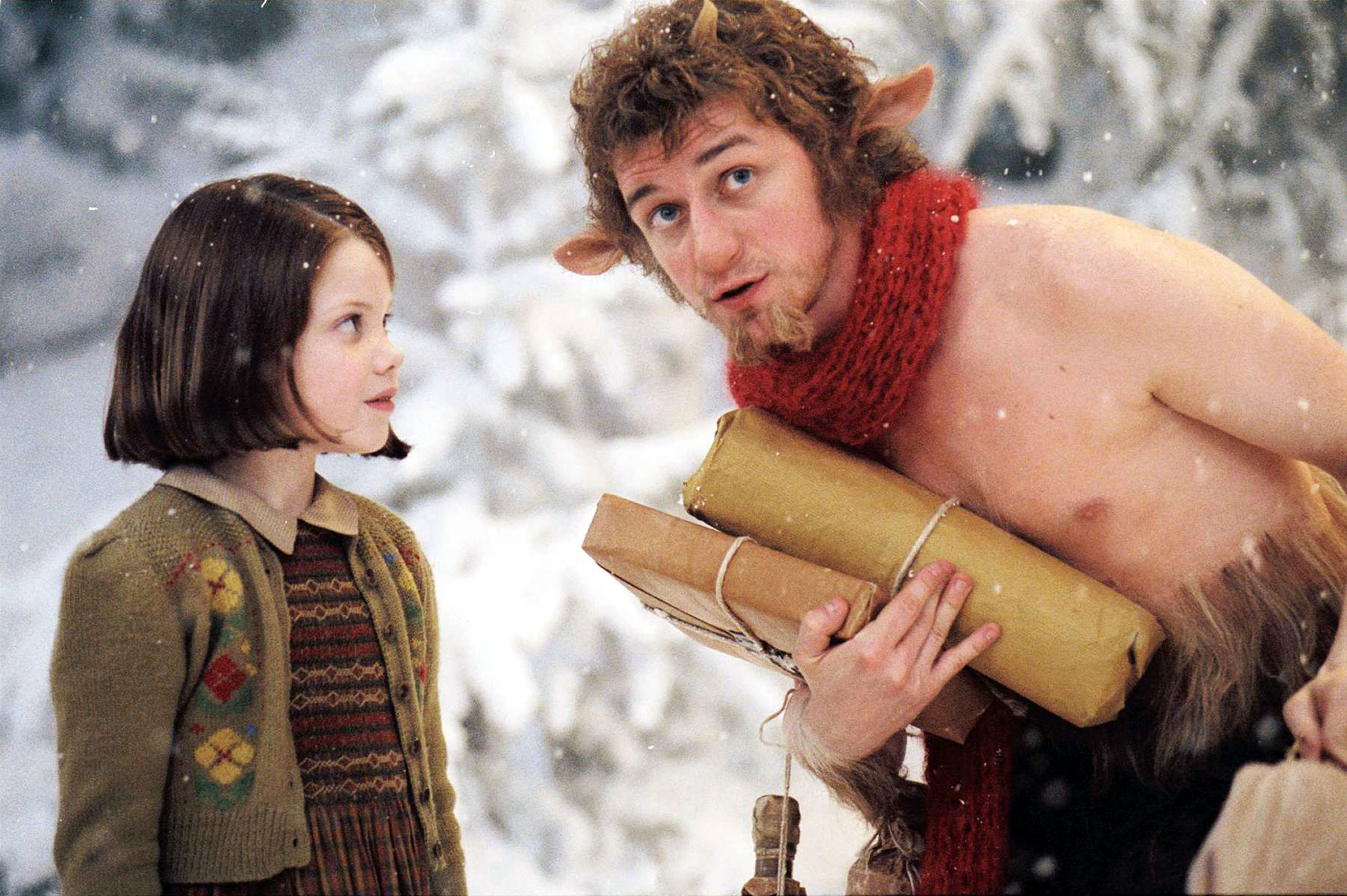 Lucy Pevensie and Mr. Tumnus from &quot;The Chronicles of Narnia: The Lion, the Witch and the Wardrobe&quot; in a snowy woodland scene. Mr. Tumnus holds wrapped packages