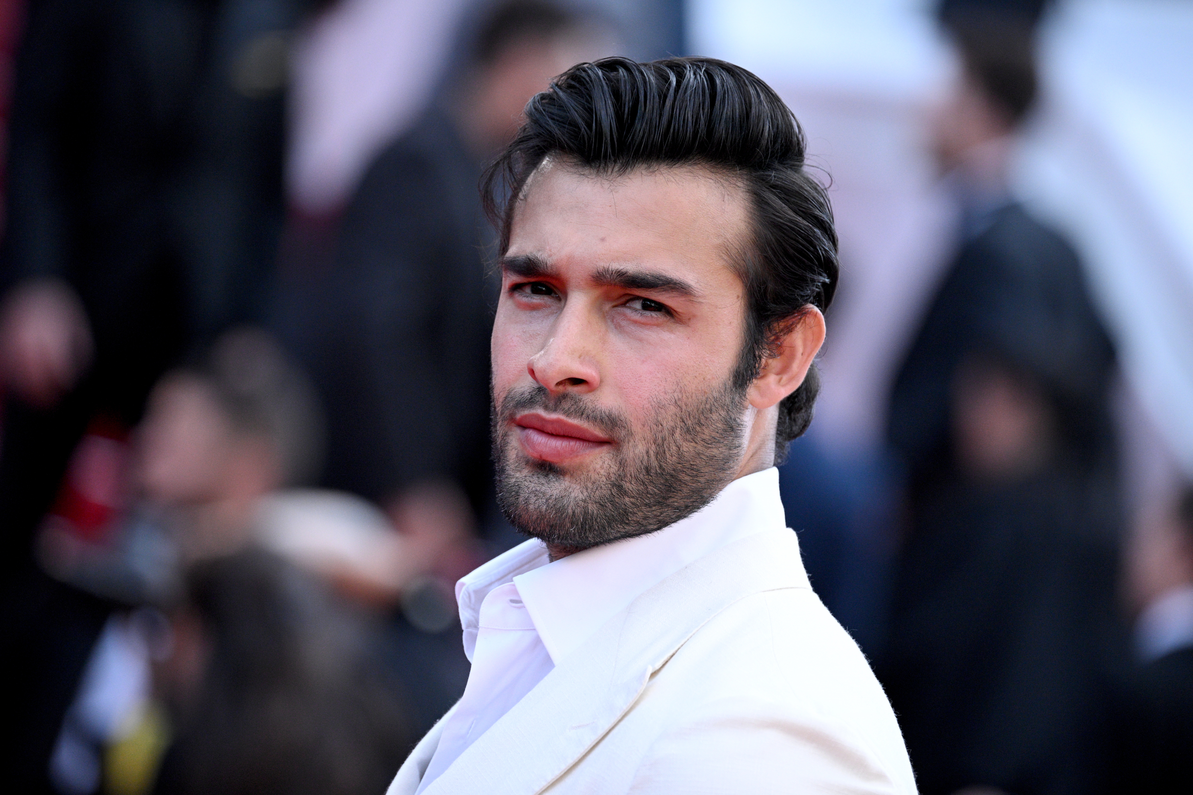 Unknown man in a white suit jacket and dress shirt on a red carpet