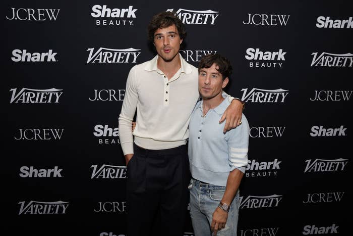 Jacob Elordi and Chase Stokes at Variety event. Jacob wears a long-sleeve, collared shirt and black pants. Chase wears a blue sweater and jeans