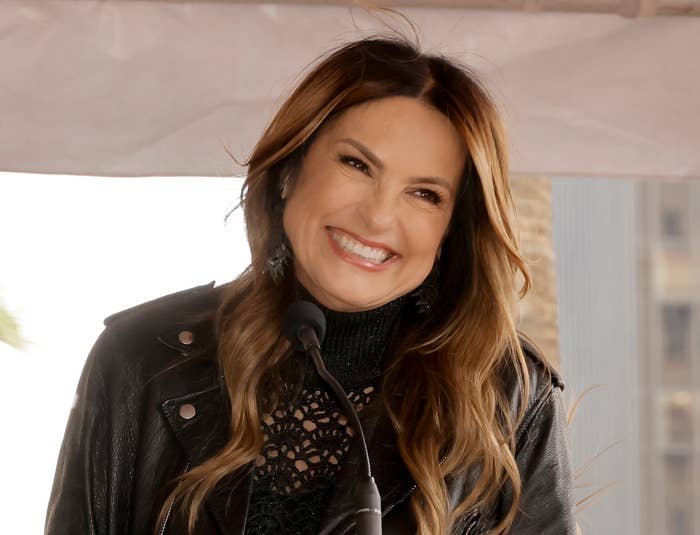 Mariska Hargitay smiles at a podium during a Hollywood Walk of Fame star ceremony, wearing a stylish lace dress and leather jacket