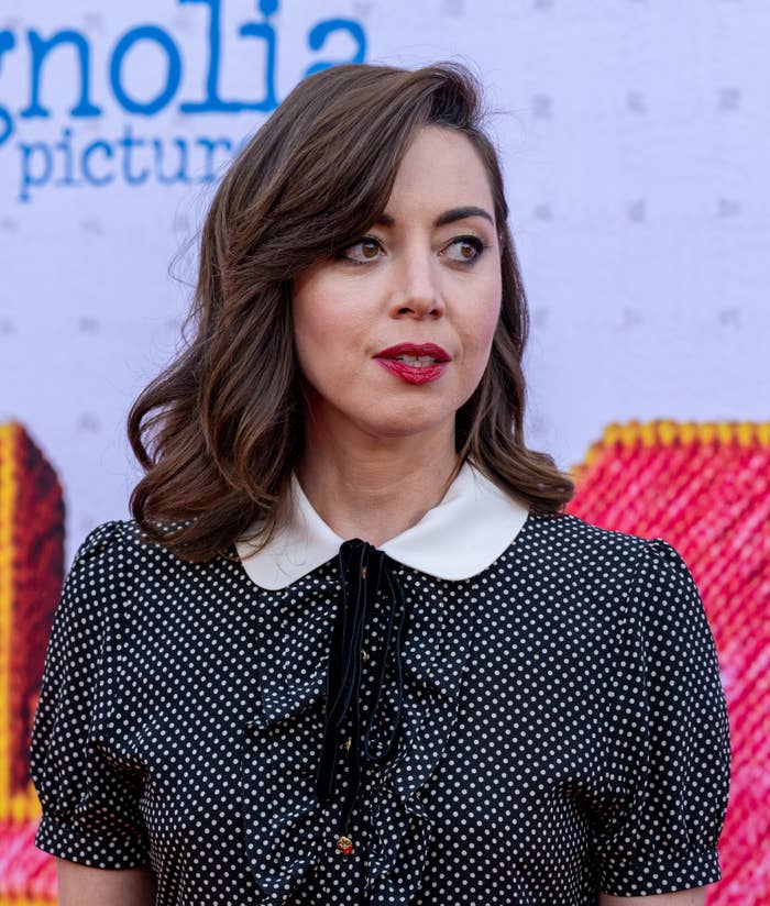 Aubrey Plaza on the red carpet, wearing a polka-dot dress with a white collar and a black ribbon tie