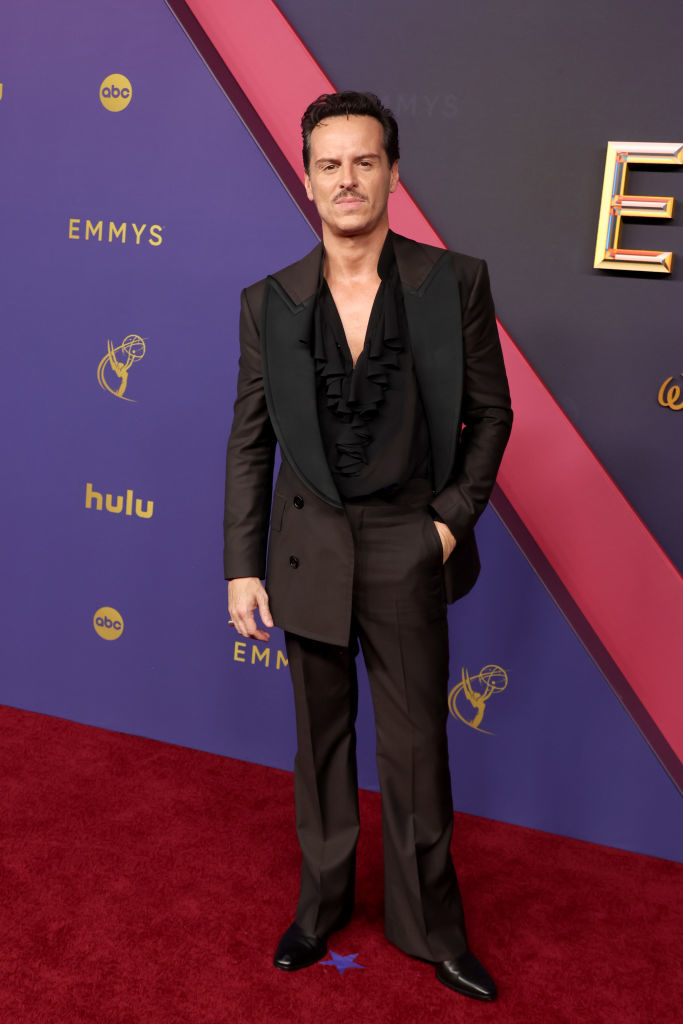 Andrew Scott on the red carpet at the Emmys, wearing a dark double-breasted suit with a ruffled black shirt