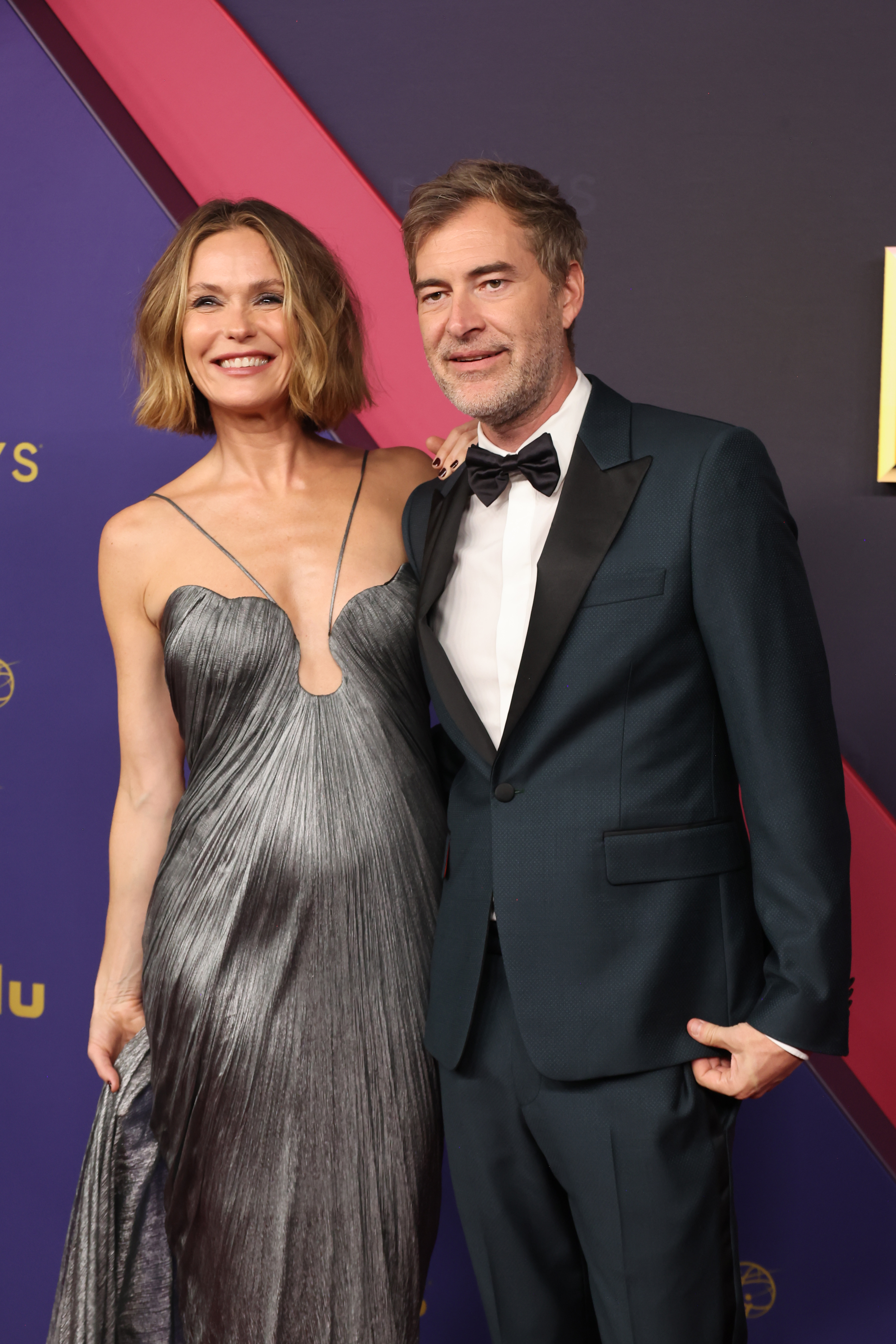 Katie Aselton in a metallic gown and Mark Duplass in a tuxedo pose together on the red carpet at a TV event