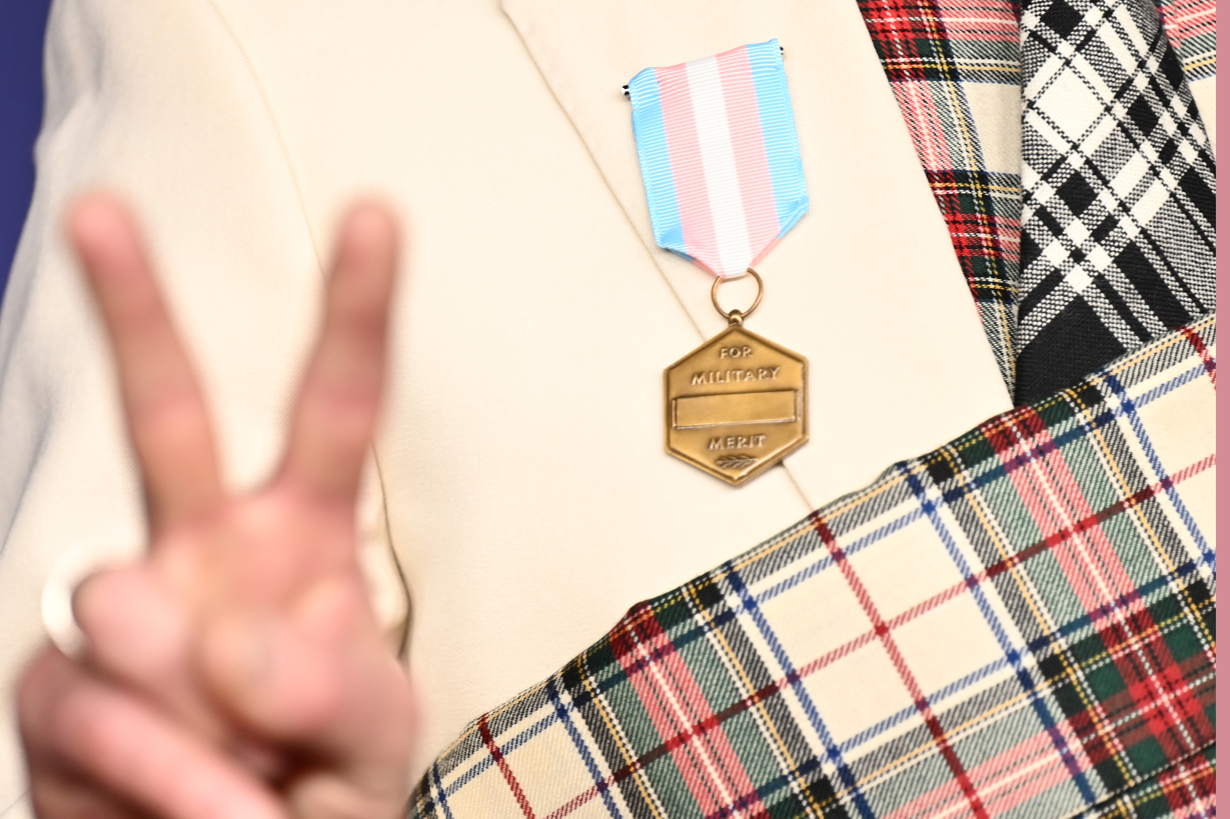 Close-up of Alan Cumming wearing a plaid outfit with a medal