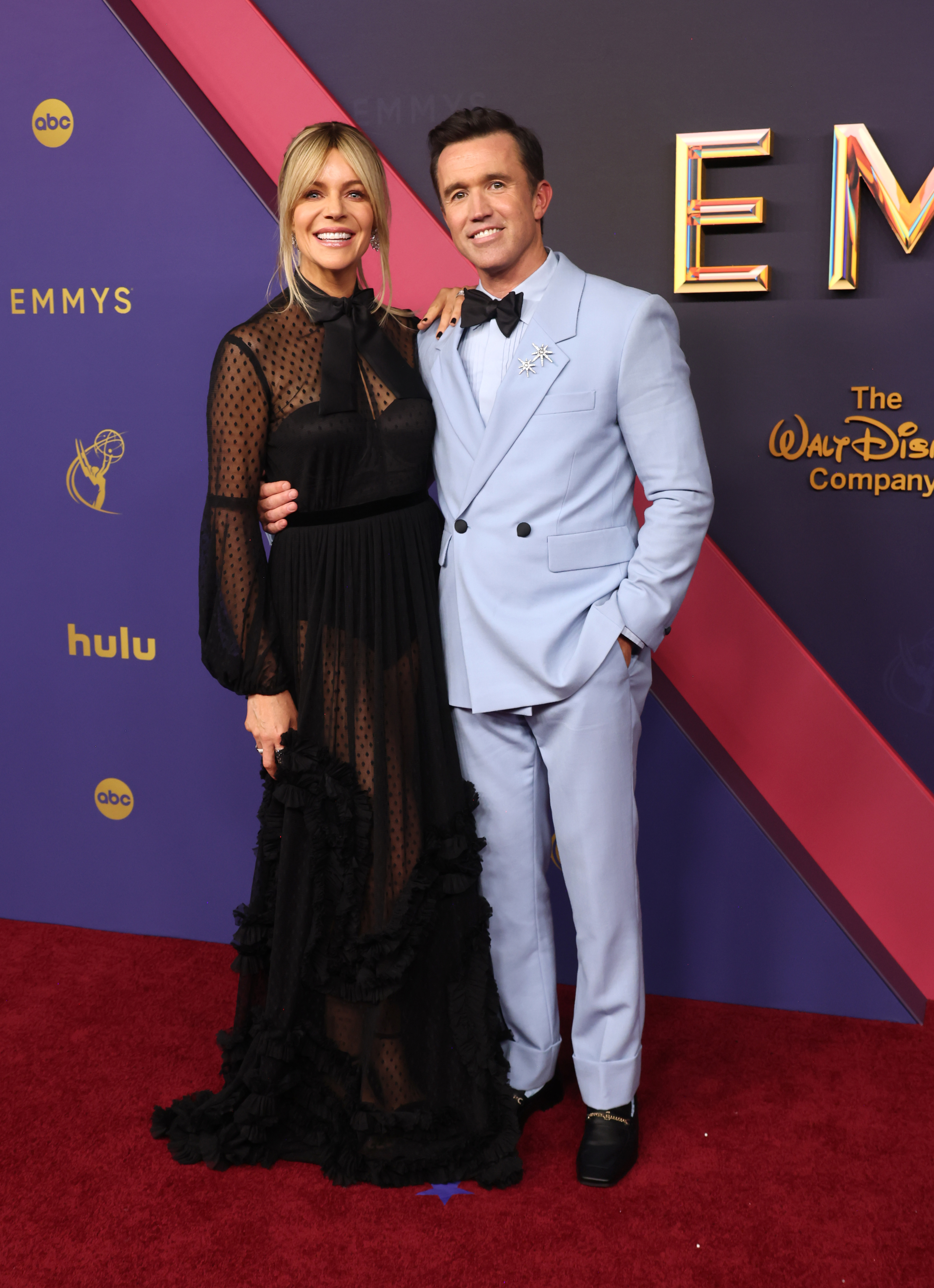 Kaitlin Olson in a sheer black dress, and Rob McElhenney in a light blue suit on the red carpet at the Emmys