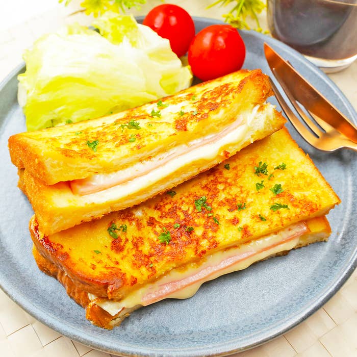 美味しそうなハムとチーズのサンドイッチ、レタスとチェリートマトが添えられたプレート。