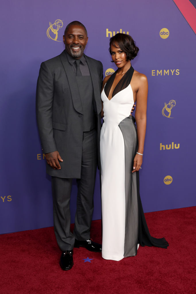Idris Elba and Sabrina Dhowre Elba pose on the red carpet; Idris wears a dark suit, Sabrina wears a sleeveless, black and white gown at the Emmys event
