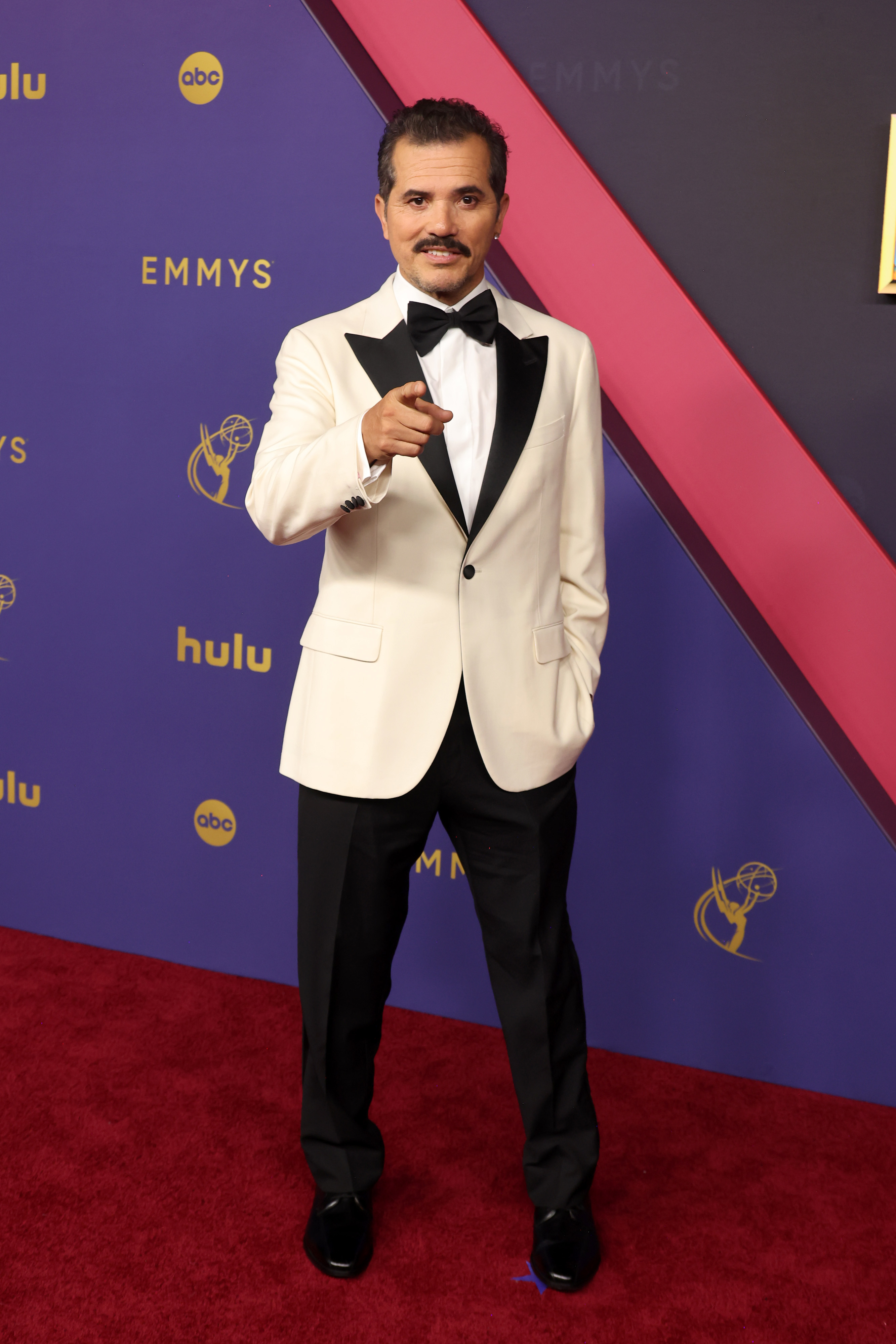 John Leguizamo on the red carpet wearing a tuxedo jacket and pants at the Emmys