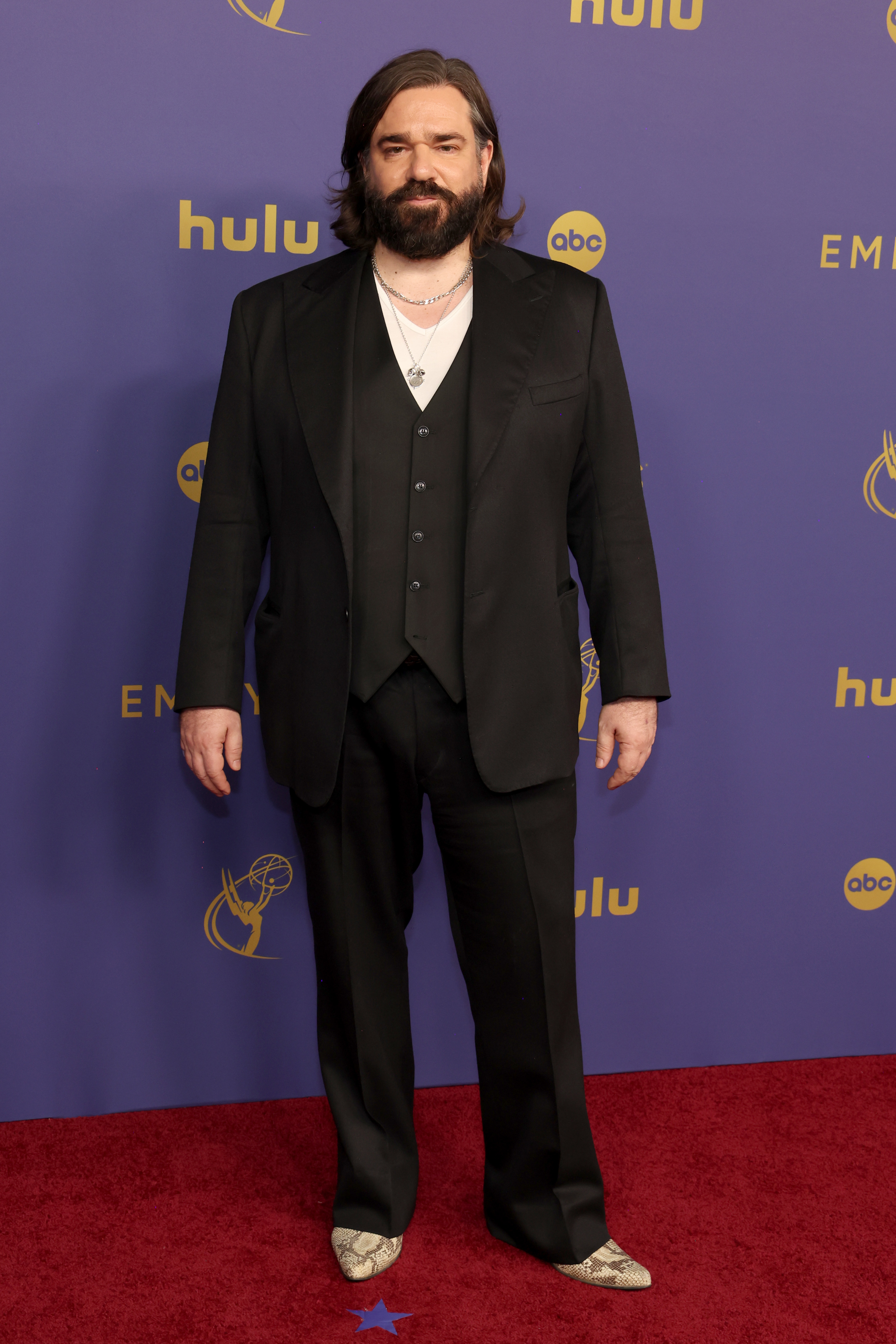 Matt Berry poses on the red carpet in a three-piece suit and shirt at the Emmys event